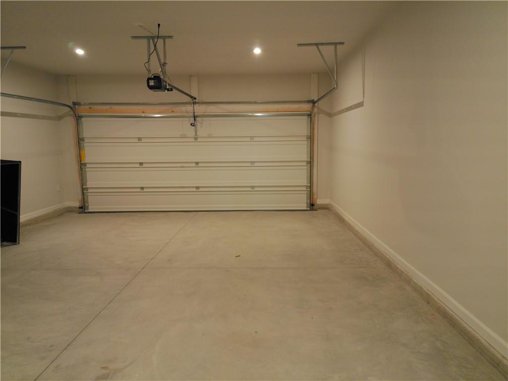 Spacious 2-car garage with overhead door opener and wall-mounted shelves in Davidson Homes The Cary A, Winder, Georgia