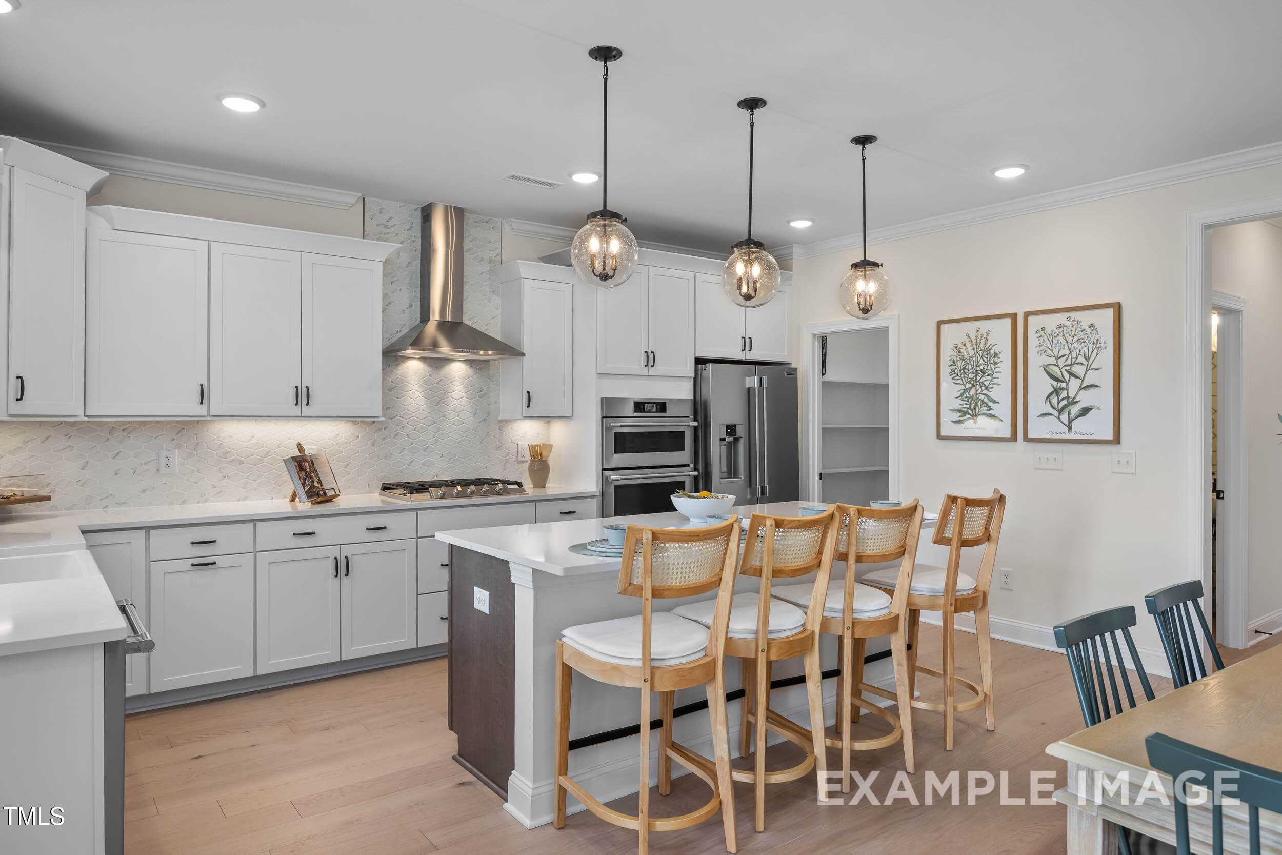 Modern white kitchen with large island, stainless appliances, pendant lights in Davidson Homes The Crawford B, Raleigh, NC