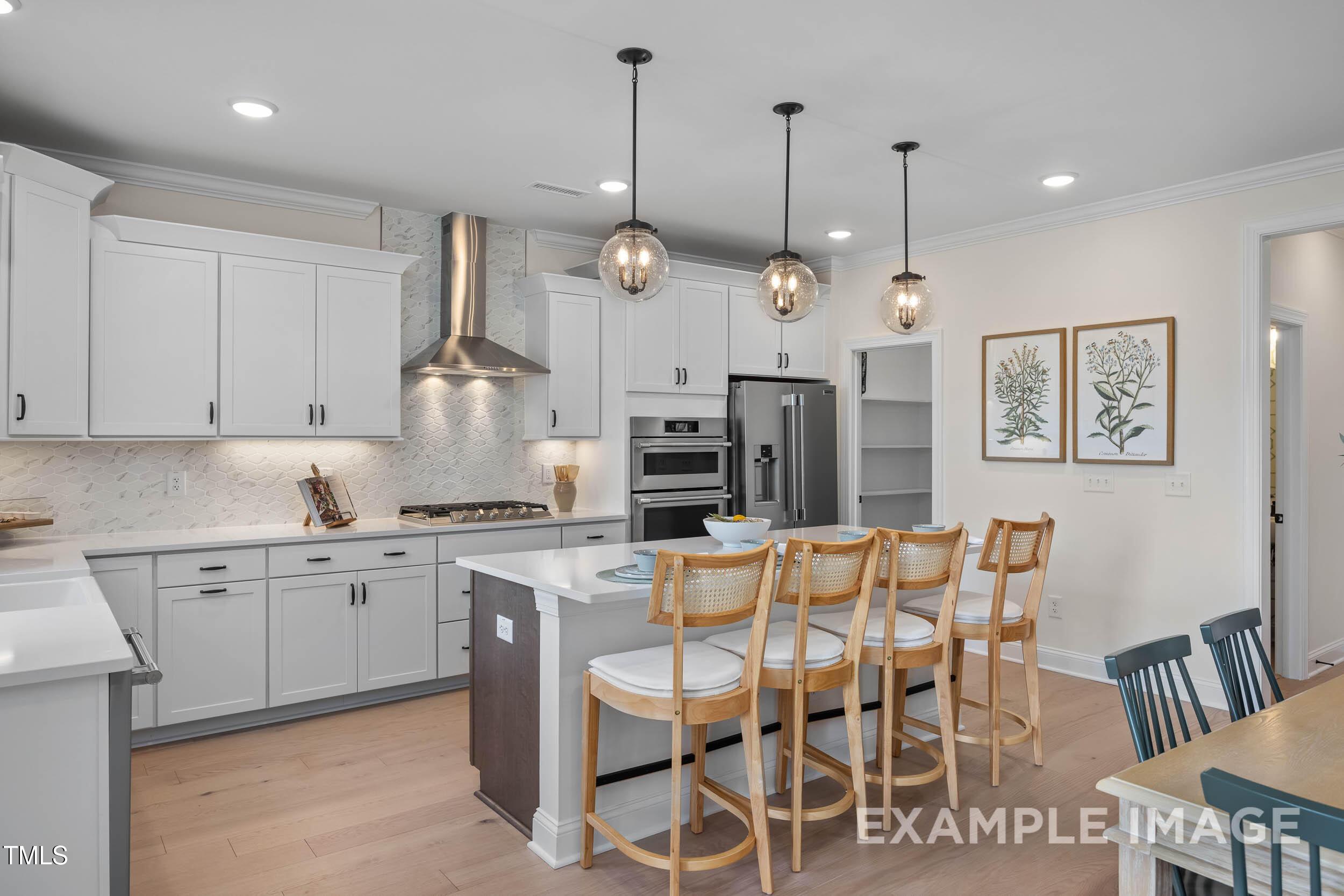 Modern white kitchen with large island, stainless appliances, pendant lights in Davidson Homes The Crawford B, Raleigh, NC