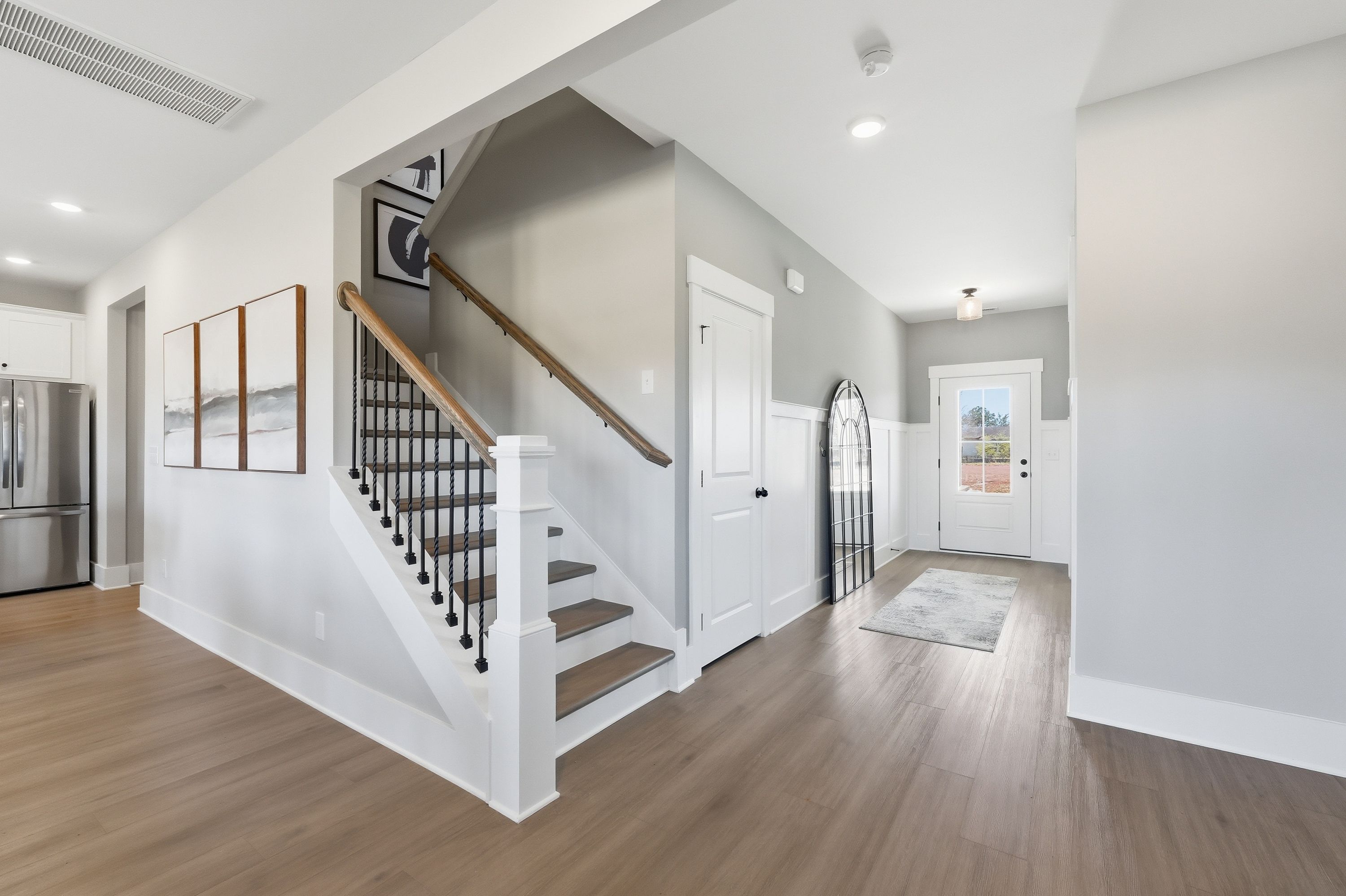 Spacious entryway with oak hardwood floors and black metal staircase in Berry Cove home, New Market Alabama