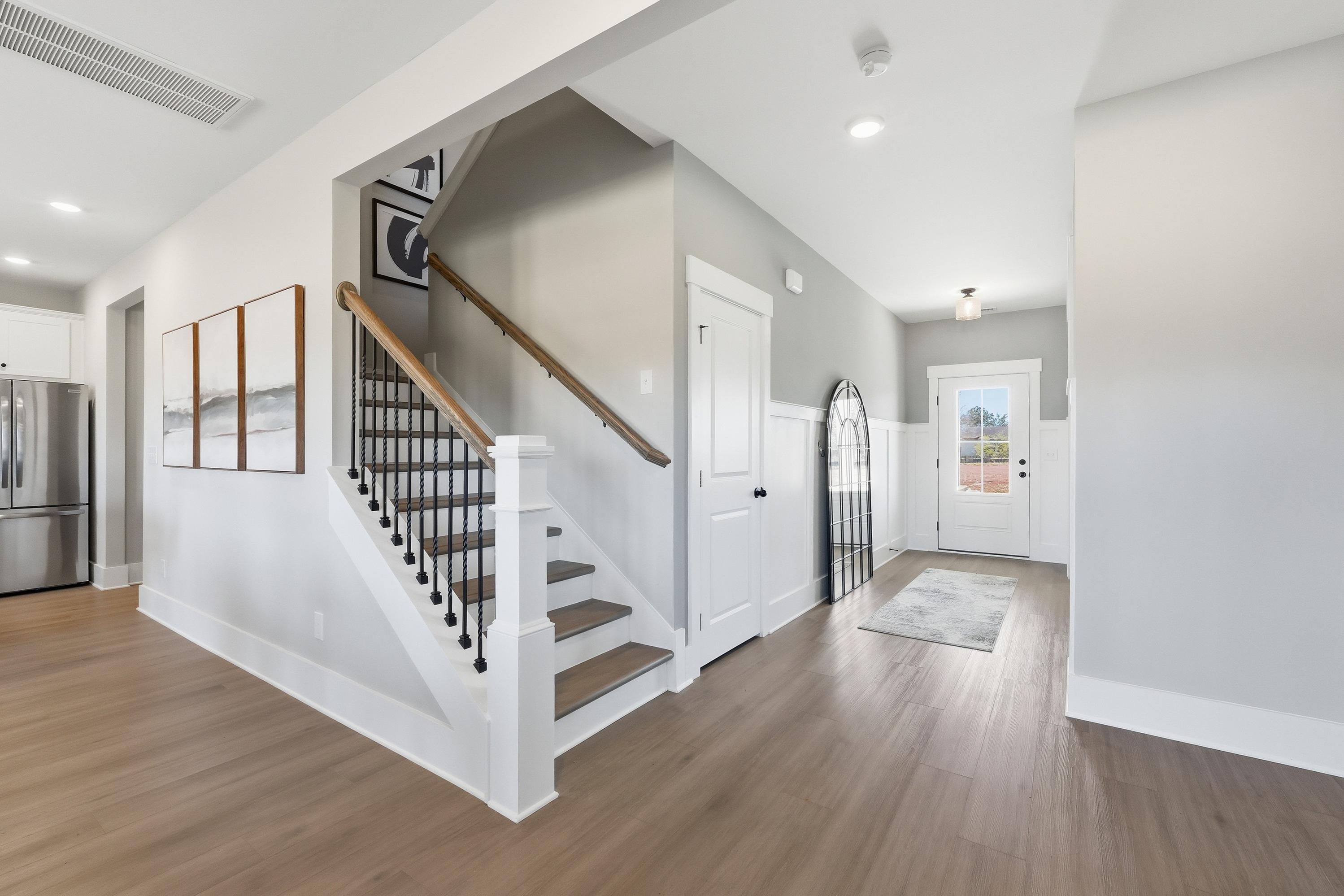 Spacious entryway with oak hardwood floors and black metal staircase in Berry Cove home, New Market Alabama