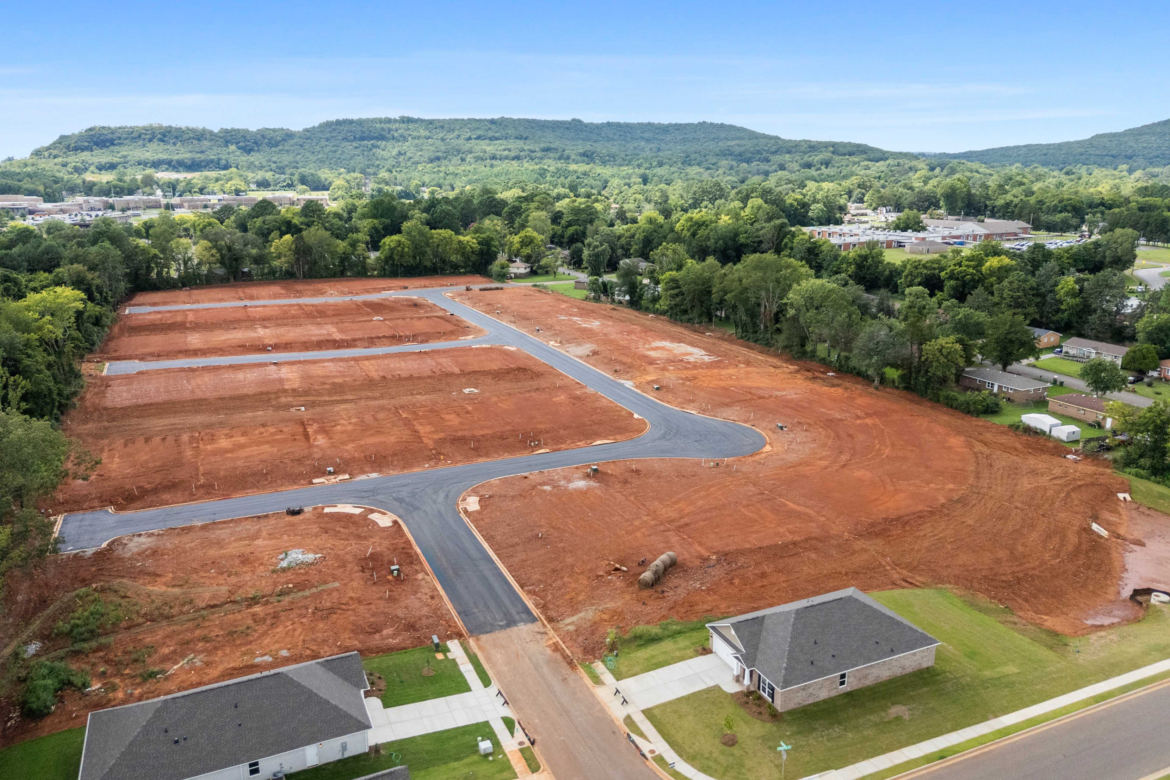 Aerial view of Blue Spring neighborhood development in Huntsville Alabama with home construction sites paved roads and wooded hills by Davidson Homes