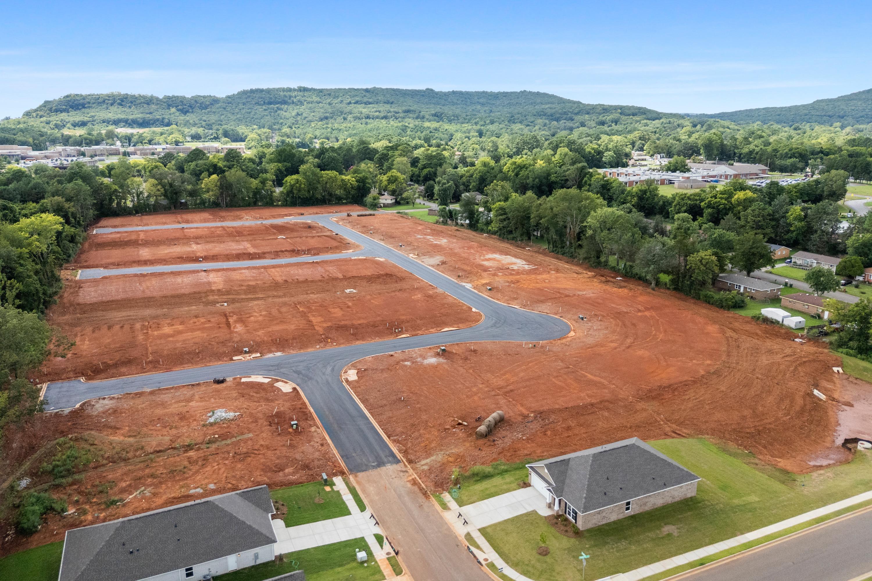 Aerial view of Blue Spring neighborhood development in Huntsville Alabama with home construction sites paved roads and wooded hills by Davidson Homes