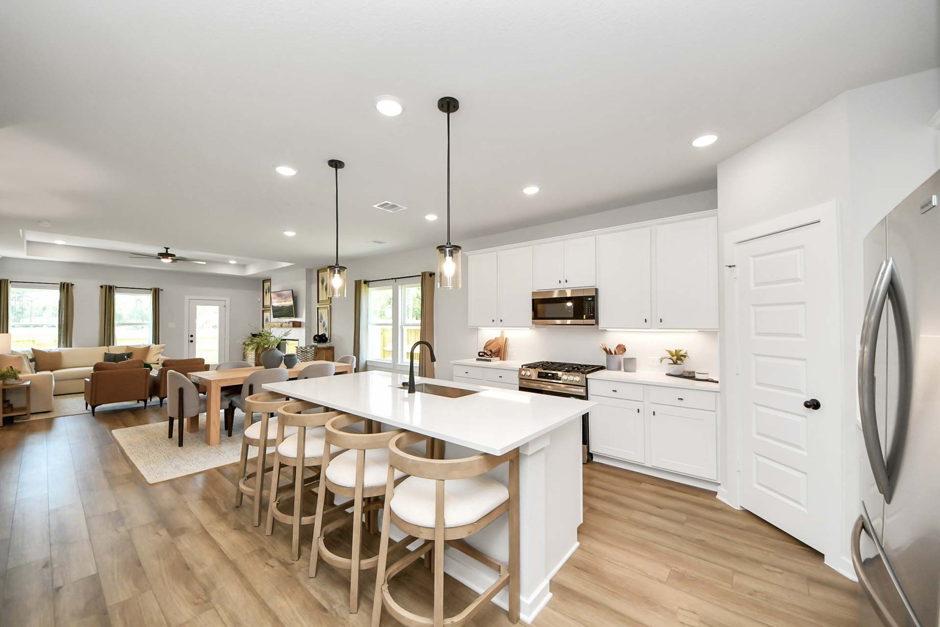 Open-concept kitchen and dining area at Enclave at Newport in Crosby, TX, featuring white cabinets and a large island.