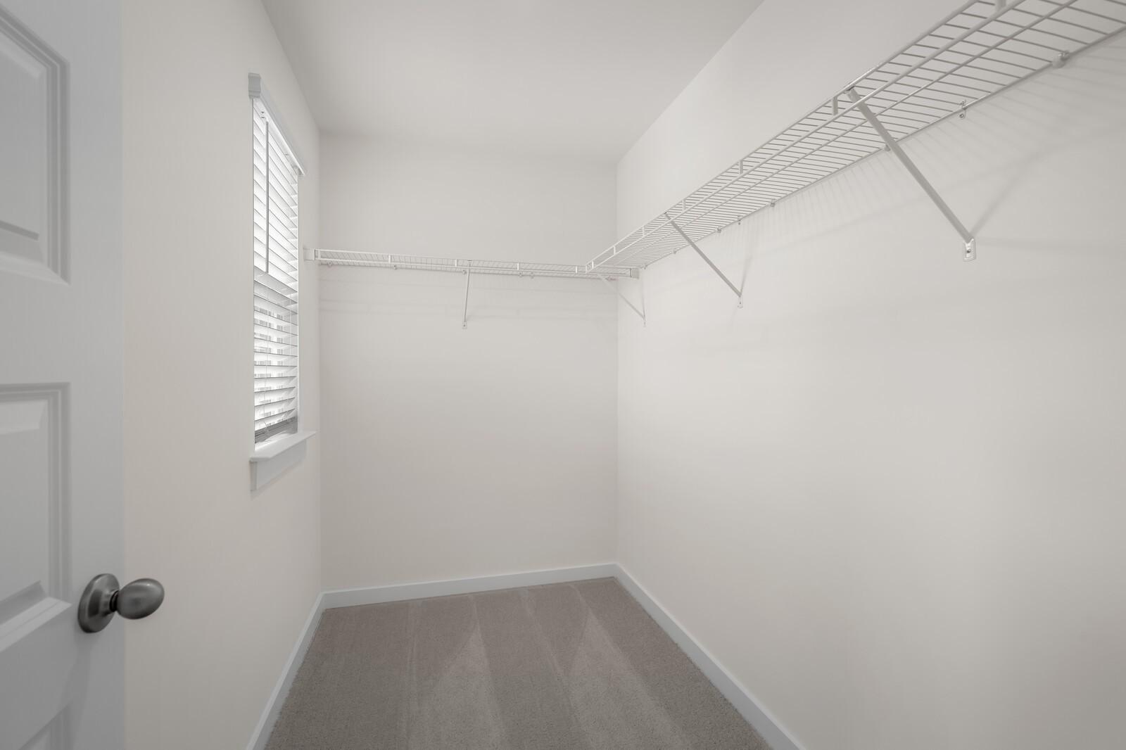 Walk-in closet with white wire shelving and carpeted flooring in The Willow floor plan at Woods Crossing, Gallatin, TN.
