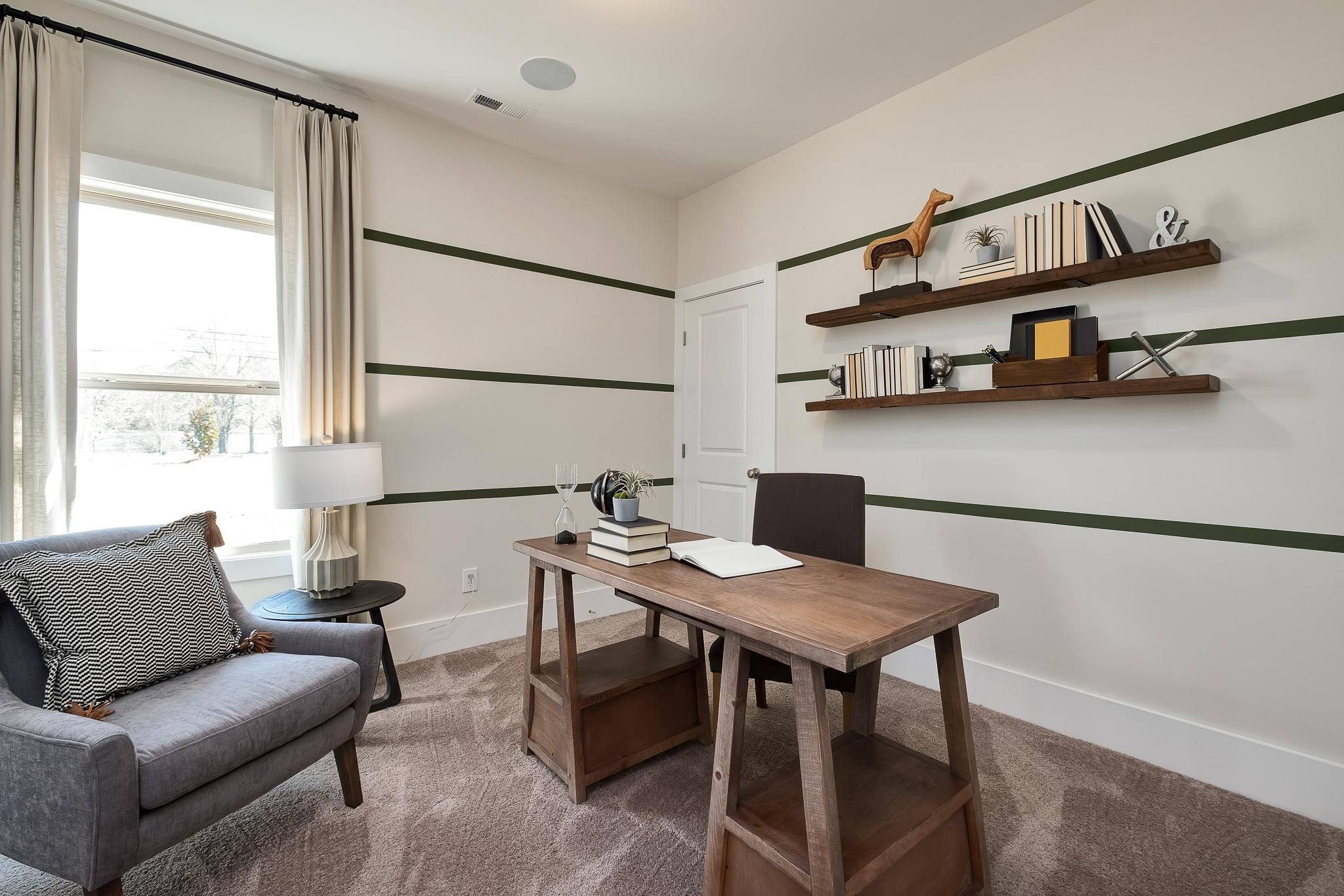Cozy home office at Magnolia Preserve in Hartselle Alabama with wooden desk, bookshelves, armchair, and green accent walls