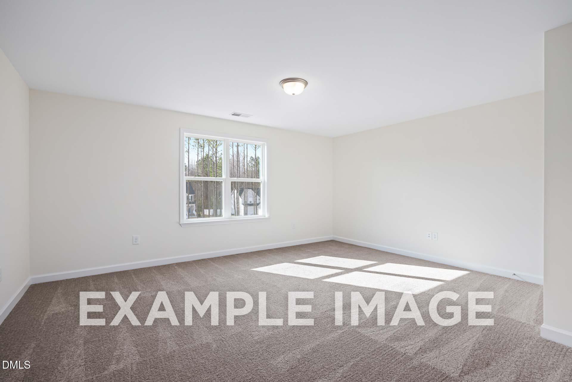 Bright empty bedroom with large windows, neutral walls, and carpeted floor in The Ash B by Davidson Homes, Zebulon, NC