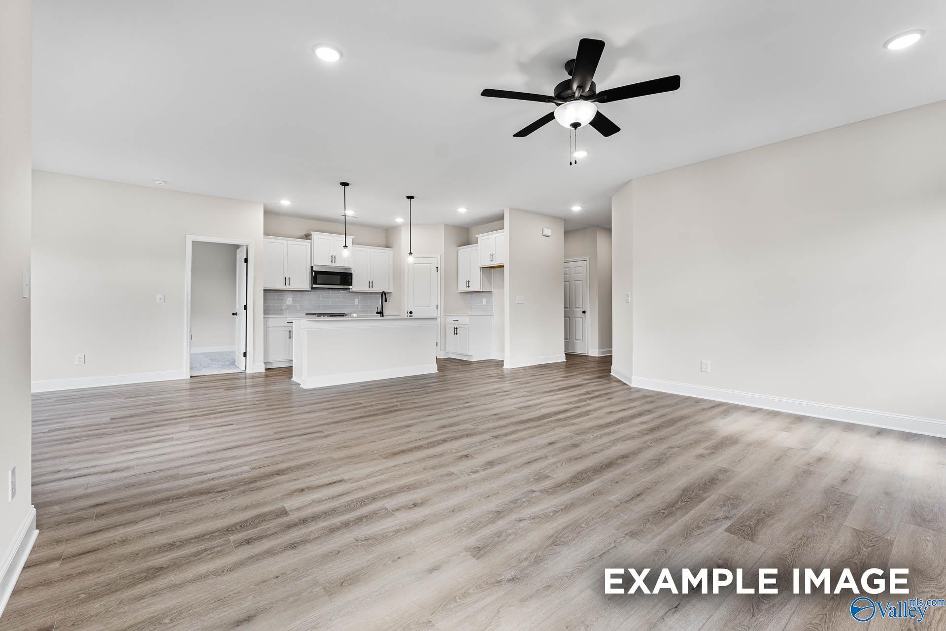 Open-concept living room and kitchen with white cabinets in The Franklin B floor plan by Davidson Homes in Harvest, AL.