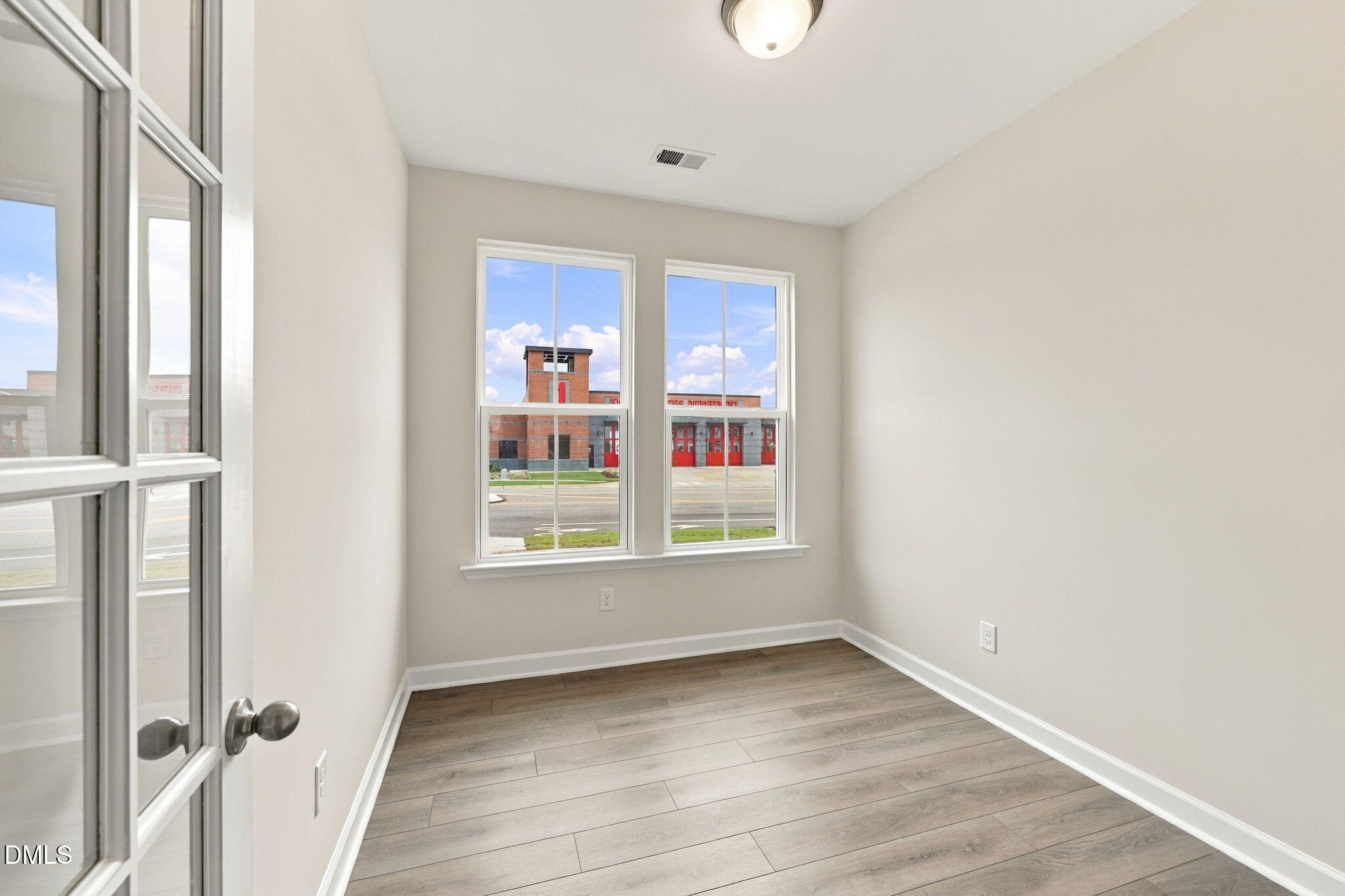 Bright empty bedroom with wood-look flooring and double windows in Davidson Homes The Alexander B, Knightdale, North Carolina