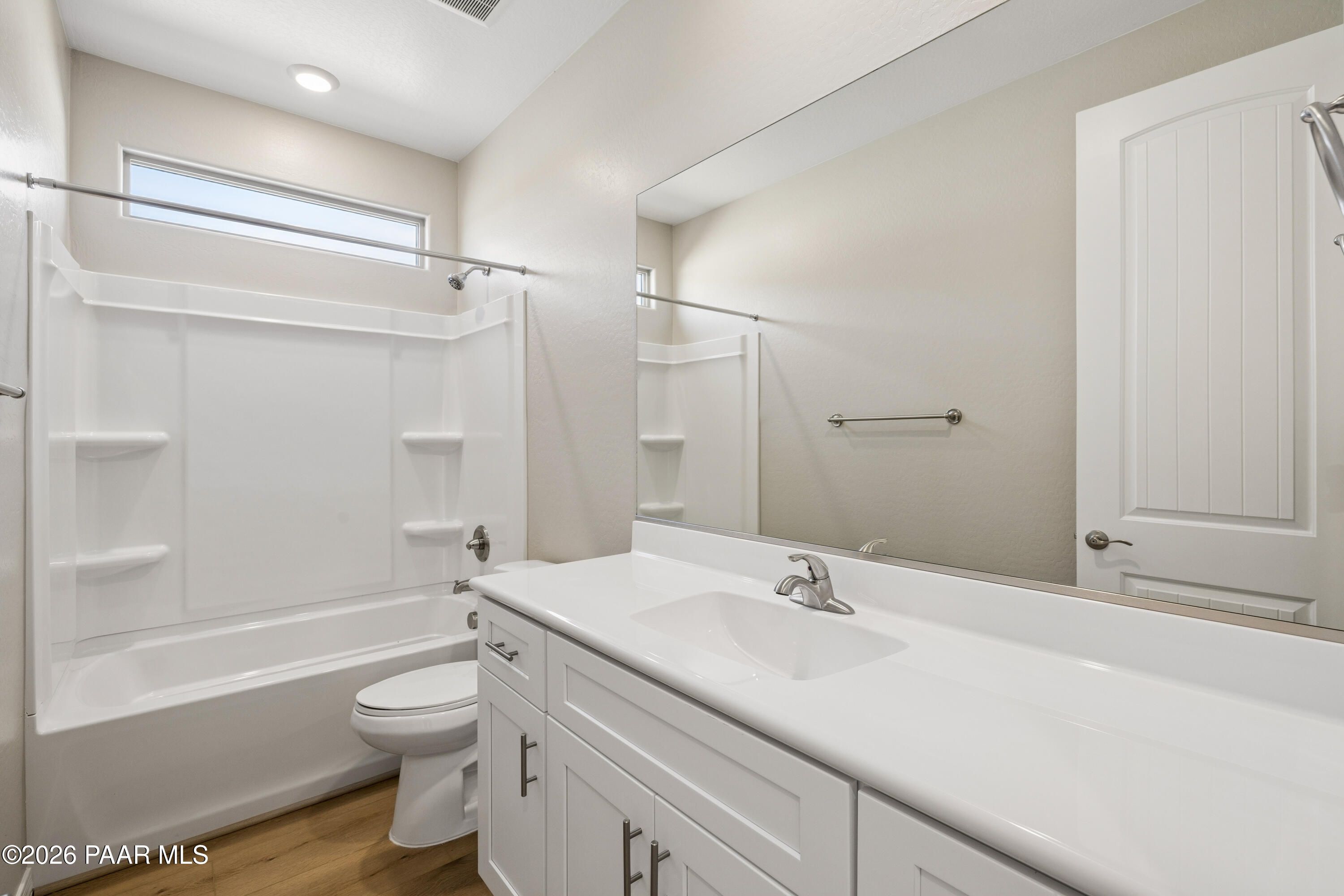 Bright full bathroom with white tub-shower combo, vanity, and mirror in Davidson Homes The Harmony A, Prescott Valley, Arizona