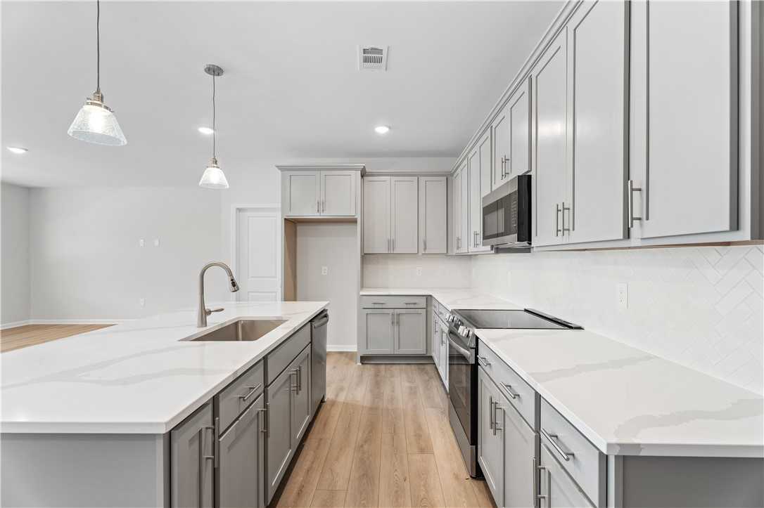 Modern kitchen with white shaker cabinets, quartz countertops, stainless appliances in Davidson Homes The Luna B, Opelika