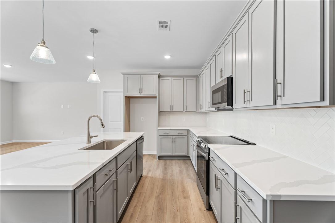Modern kitchen with white shaker cabinets, quartz countertops, stainless appliances in Davidson Homes The Luna B, Opelika