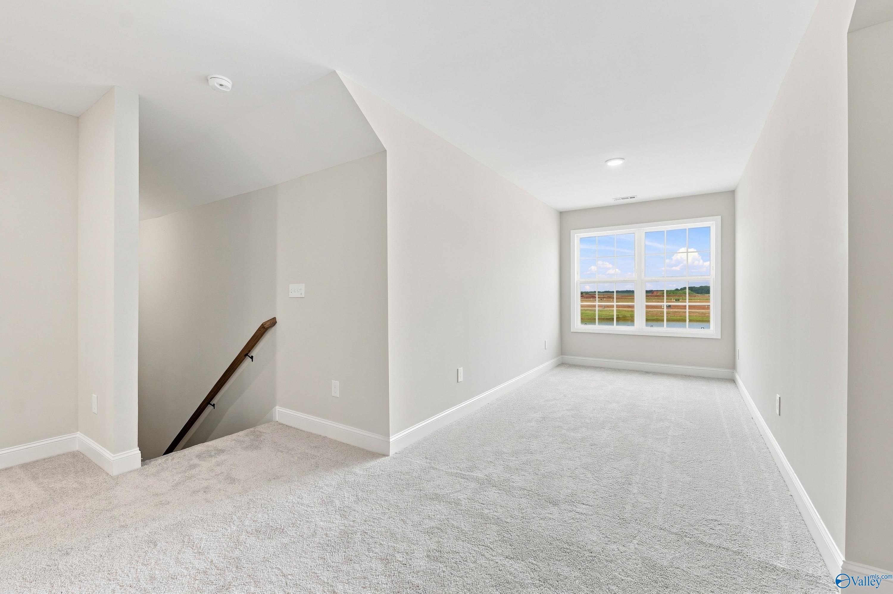 Spacious carpeted loft area in The Rockford B floor plan at Kendall Downs in Toney, Alabama.
