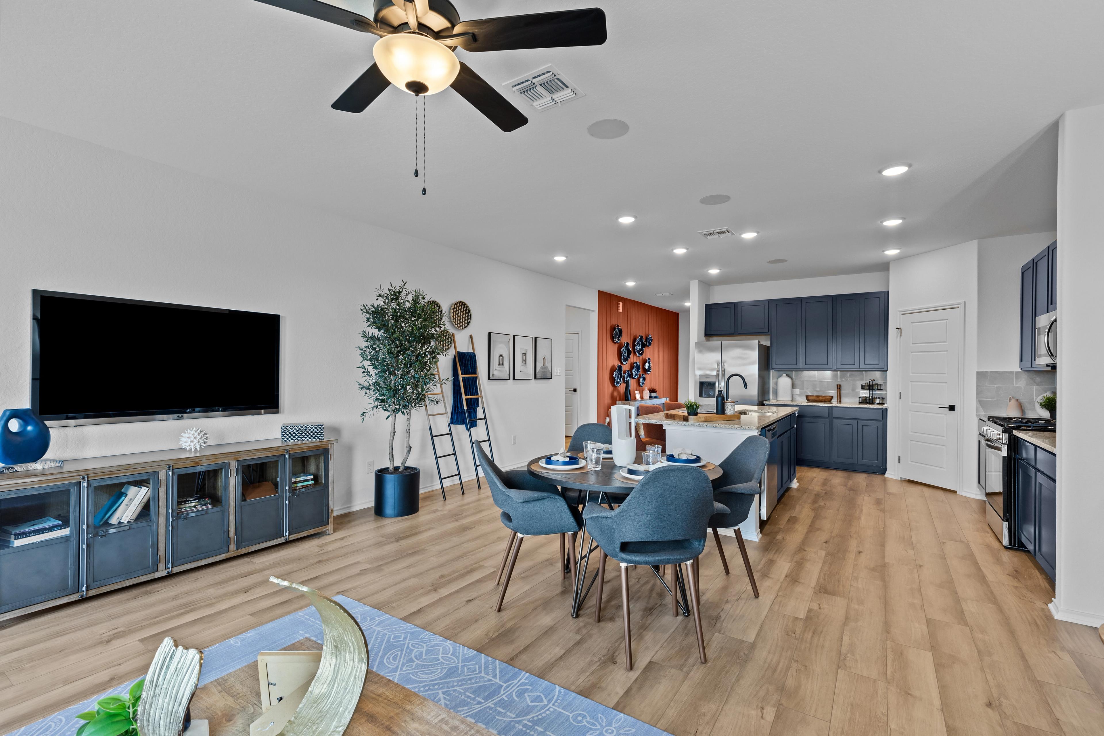 Open-concept kitchen and living area in The Douglas F with navy cabinets, large island, ceiling fan, and wood floors