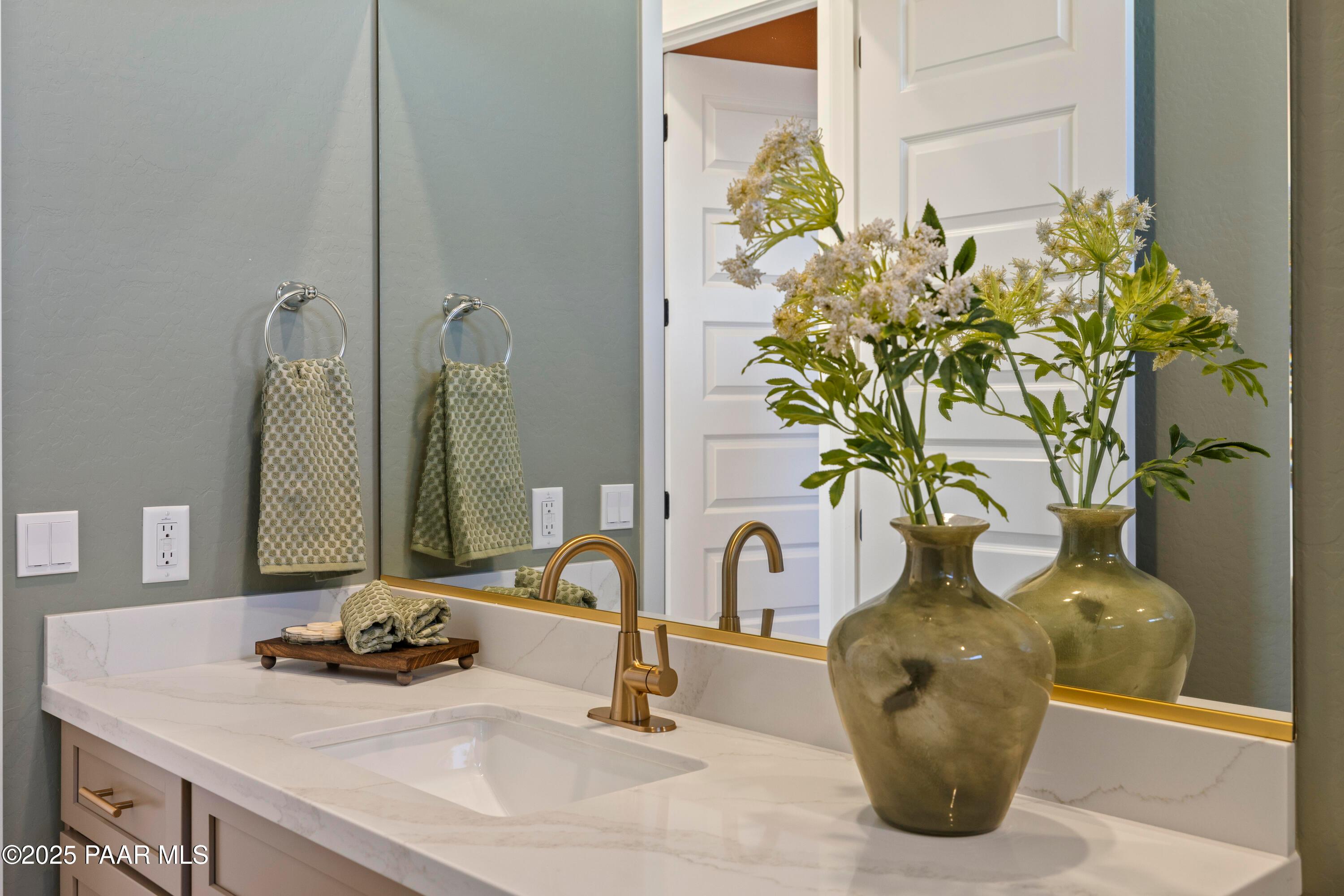 Elegant master bathroom double vanity with quartz countertop, gold faucets, and floral vase in Davidson Homes The Blaze D, Prescott AZ