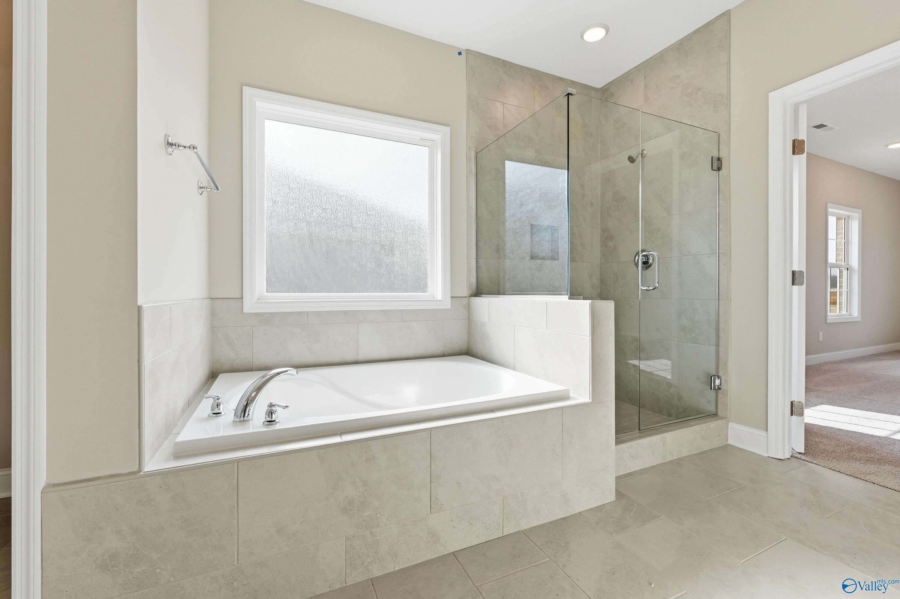 Luxurious master bathroom with soaking tub, frameless glass shower, and tiled walls in Davidson Homes The Lanier, Meridianville, Alabama