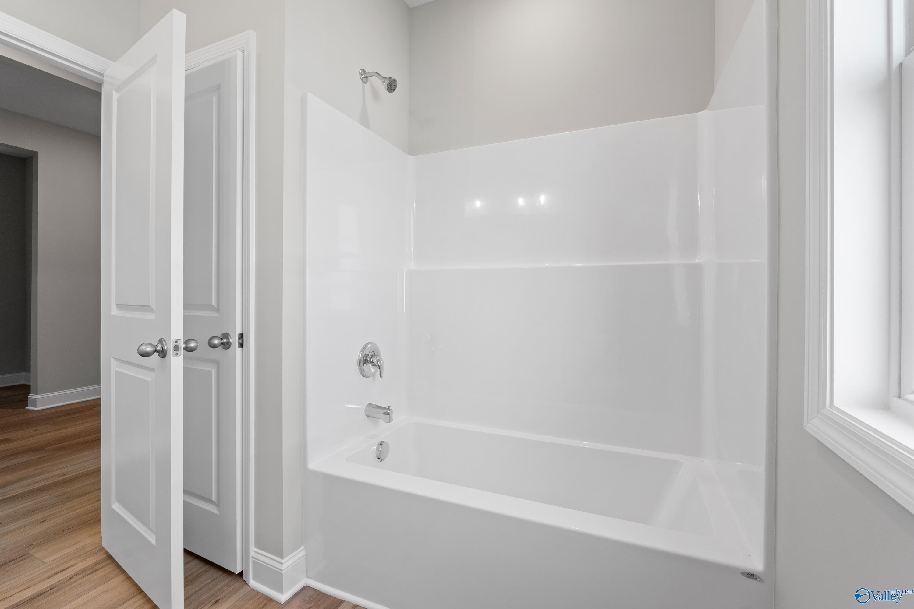 Modern bathroom featuring white tub, glass shower enclosure, and gray walls in Davidson Homes The Everett B, Toney, Alabama
