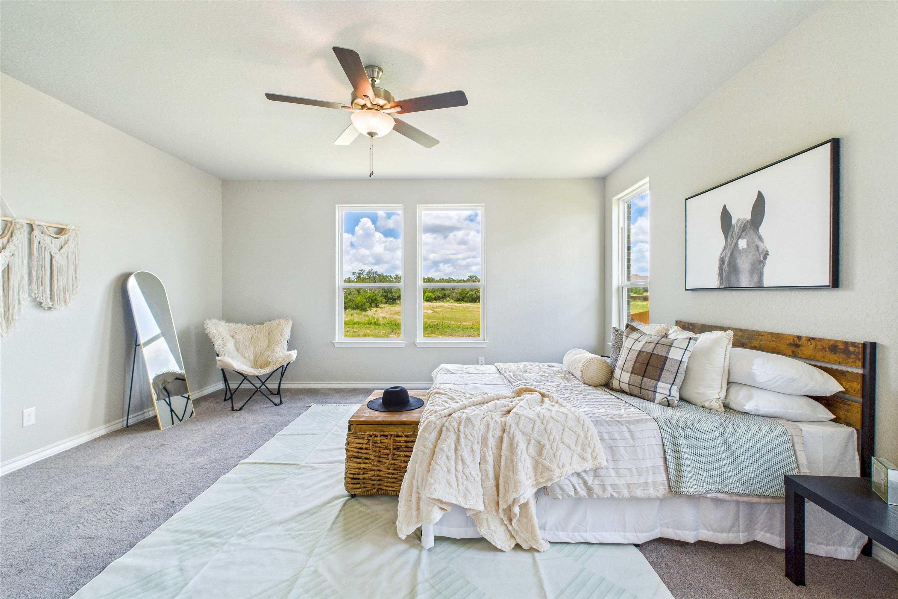 Spacious master bedroom in The Foster featuring natural light, wood-frame bed, and views of the Castroville landscape.