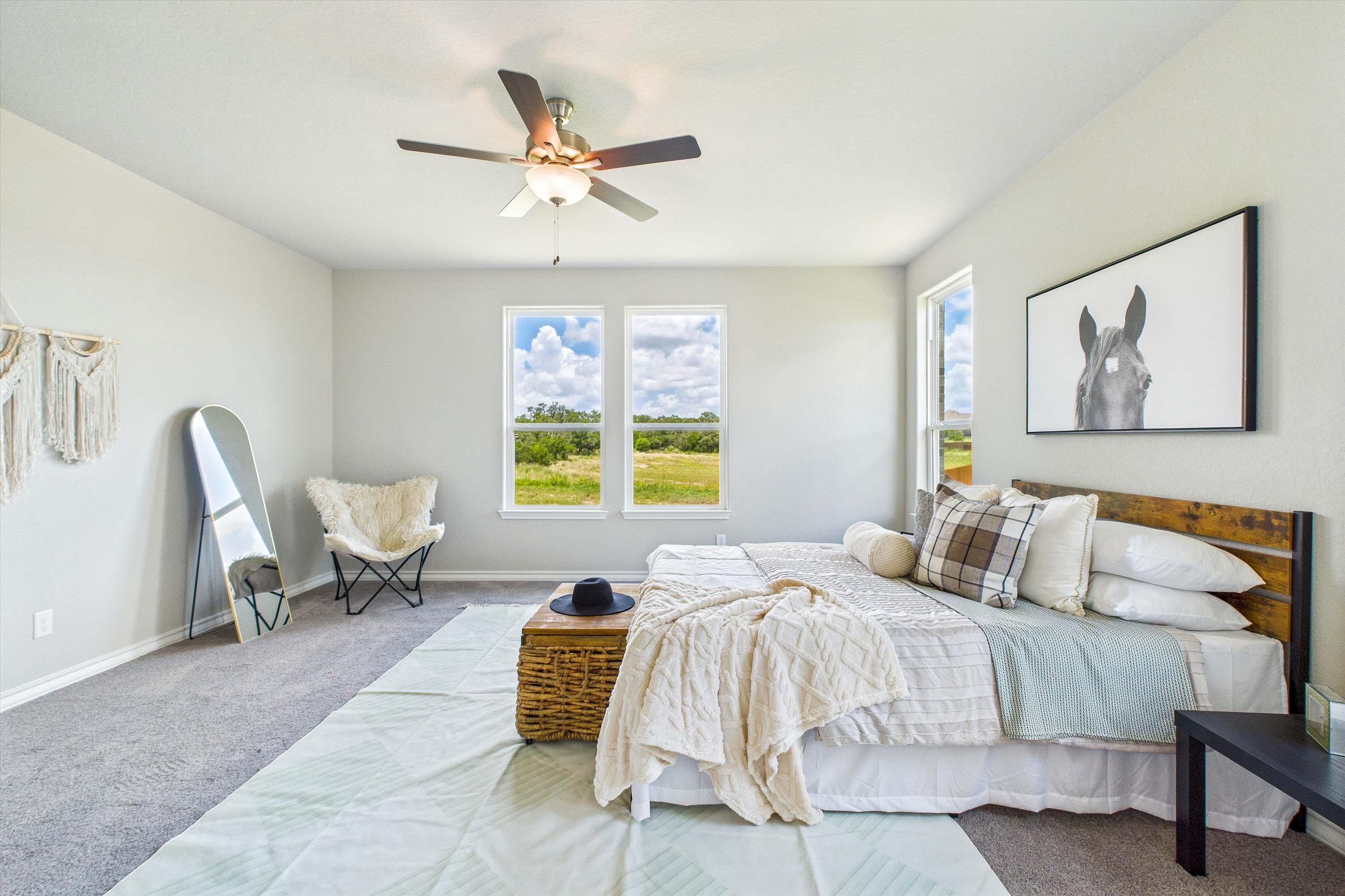 Spacious master bedroom in The Foster featuring natural light, wood-frame bed, and views of the Castroville landscape.