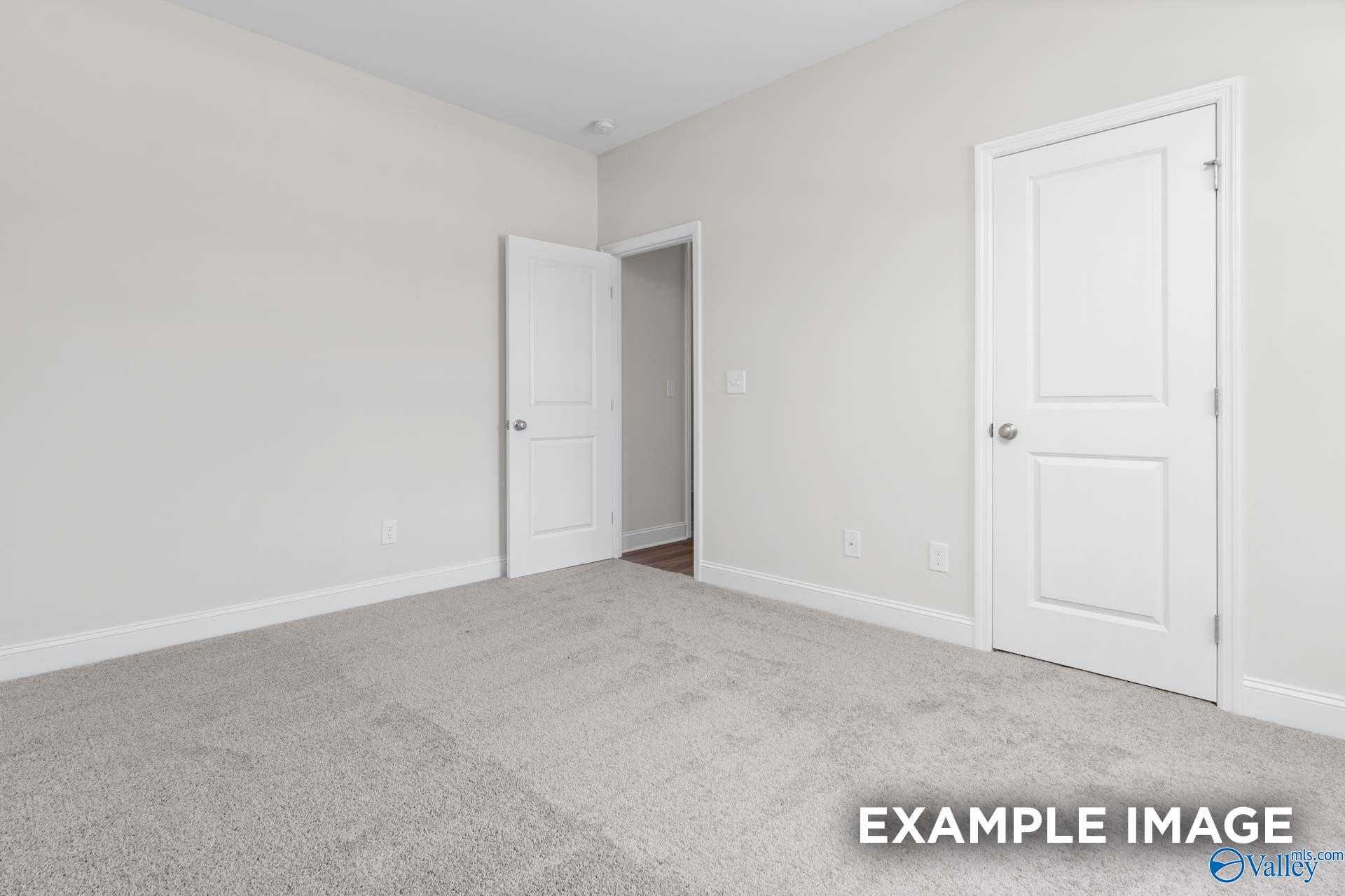 Spacious empty bedroom with neutral walls, carpet flooring, and open doorway in 4-bedroom Davidson Homes The Daphne D, Arab, Alabama