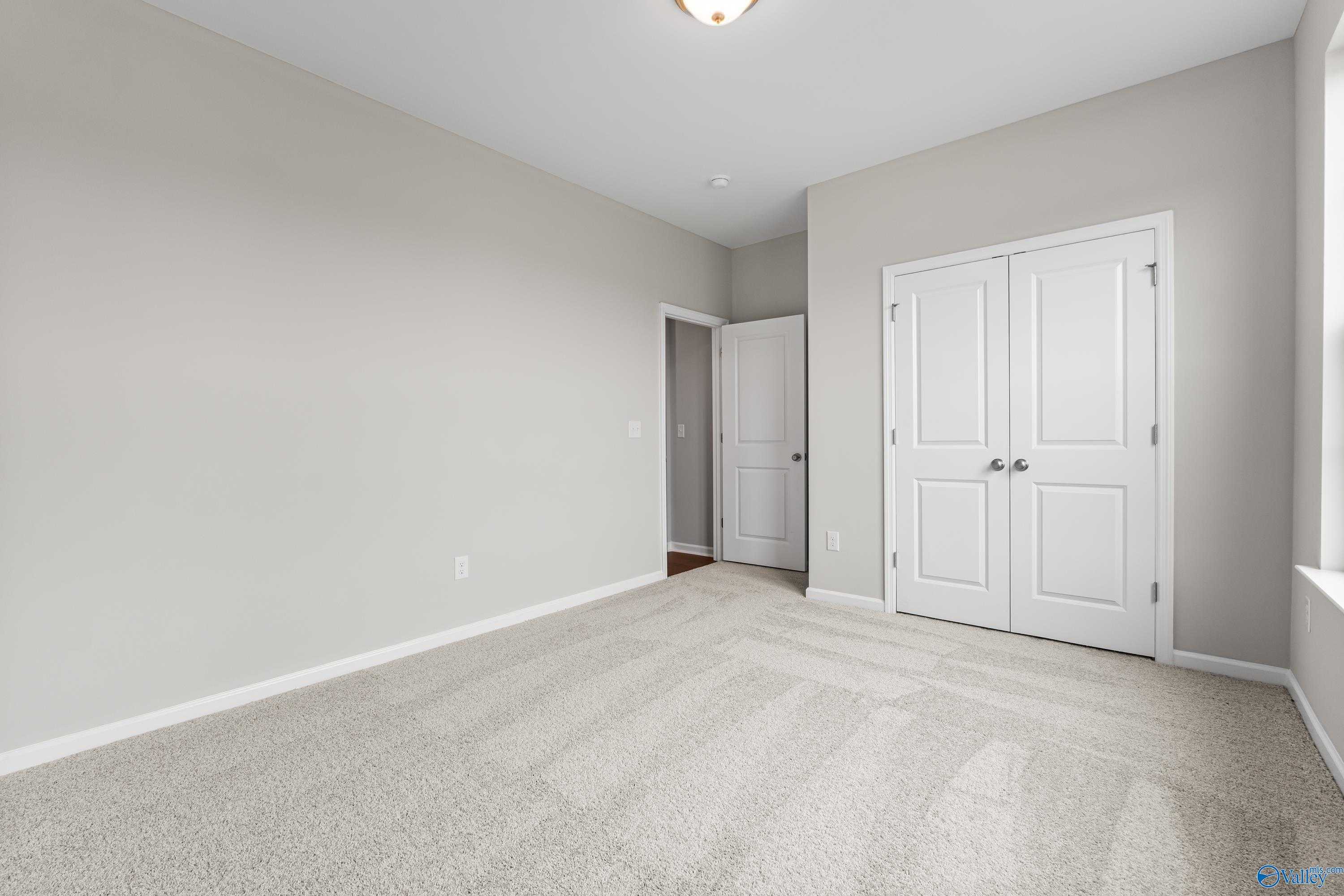 Bright secondary bedroom with gray walls, beige carpet, double closet doors in Davidson Homes The Phoenix, Fayetteville