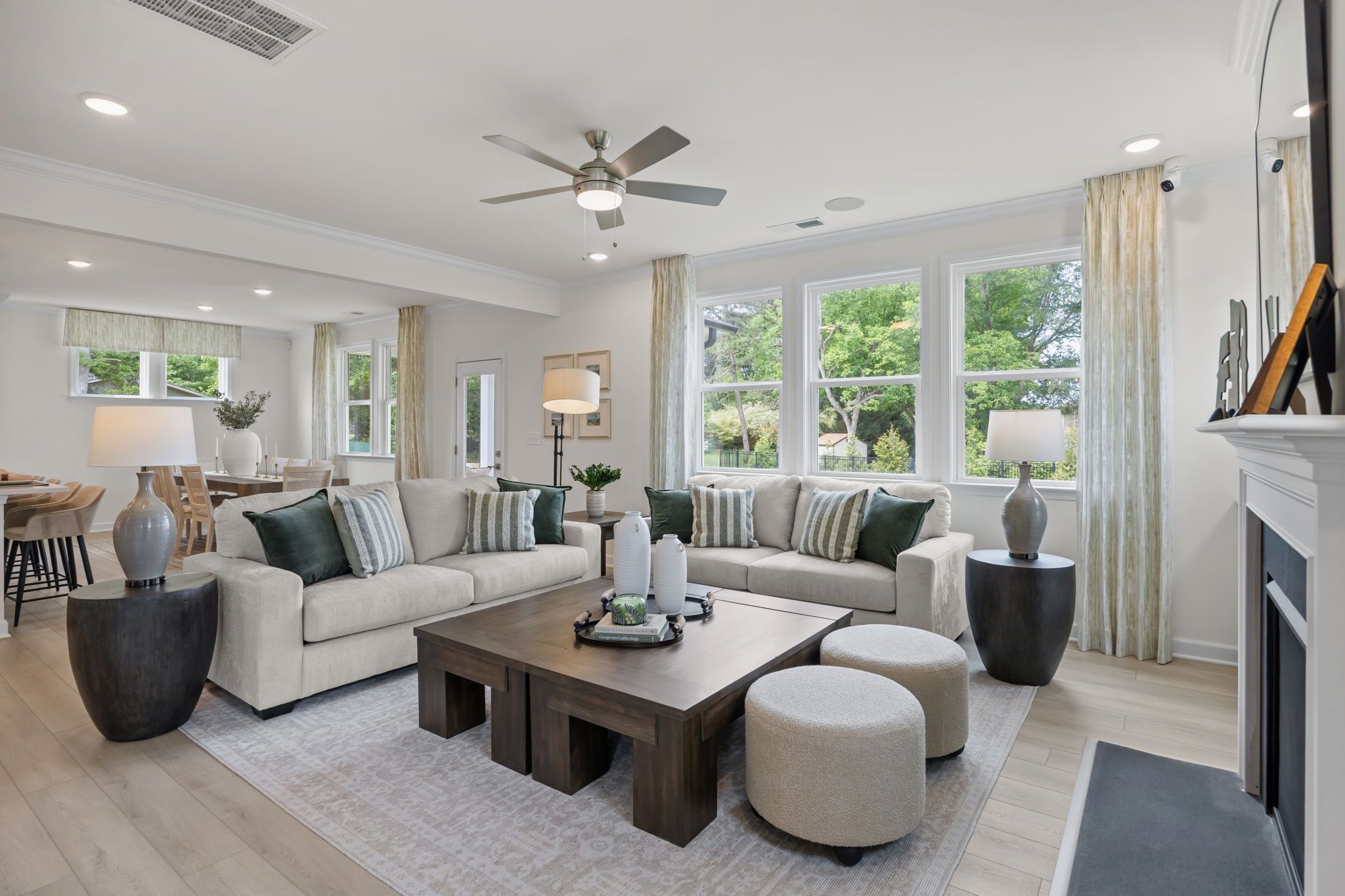 Modern open-concept kitchen in Windgate, Mooresville NC with white shaker cabinets, gray island, bar stools, stainless steel appliances, and hardwood floors