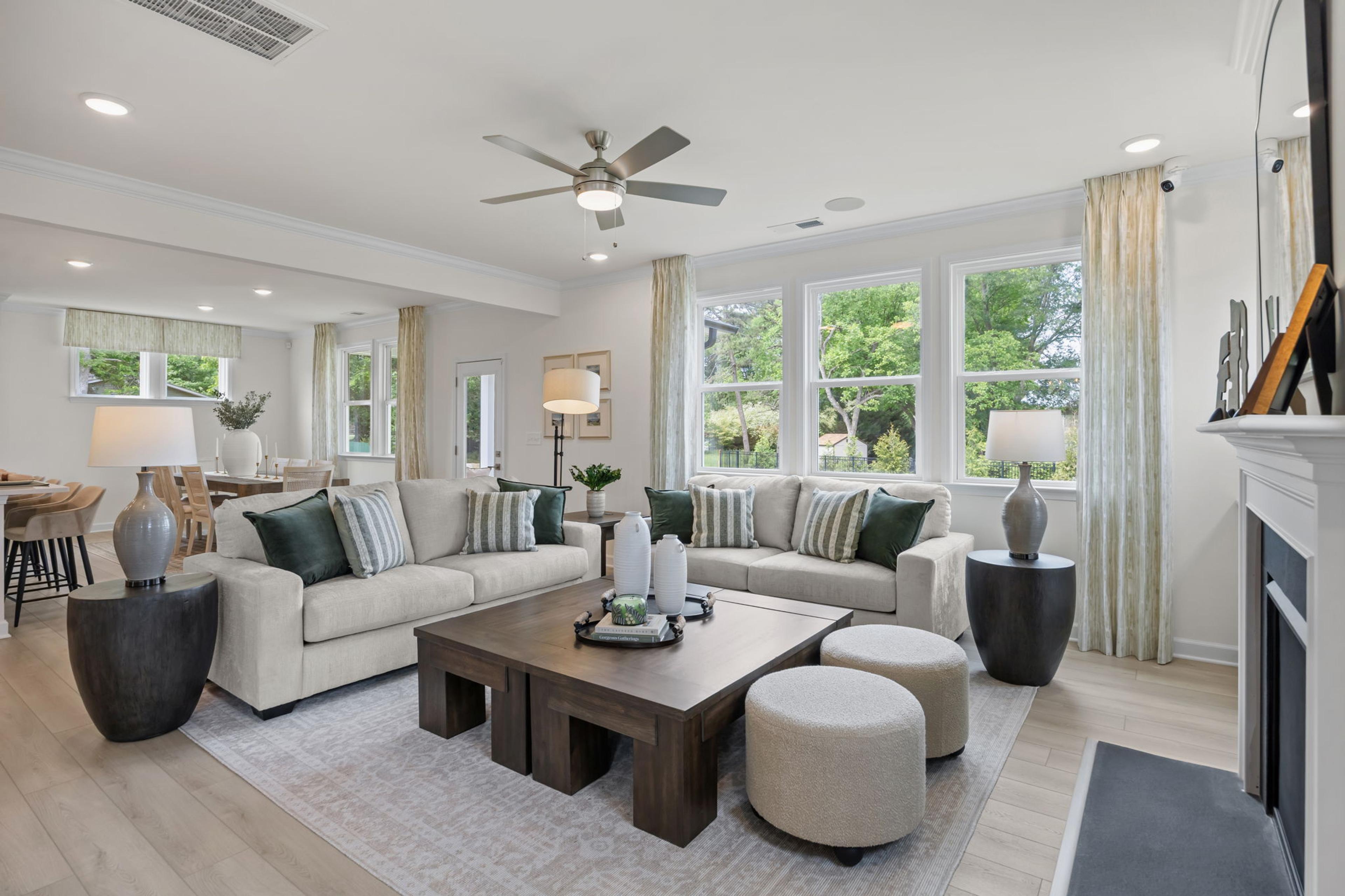 Modern open-concept kitchen in Windgate, Mooresville NC with white shaker cabinets, gray island, bar stools, stainless steel appliances, and hardwood floors