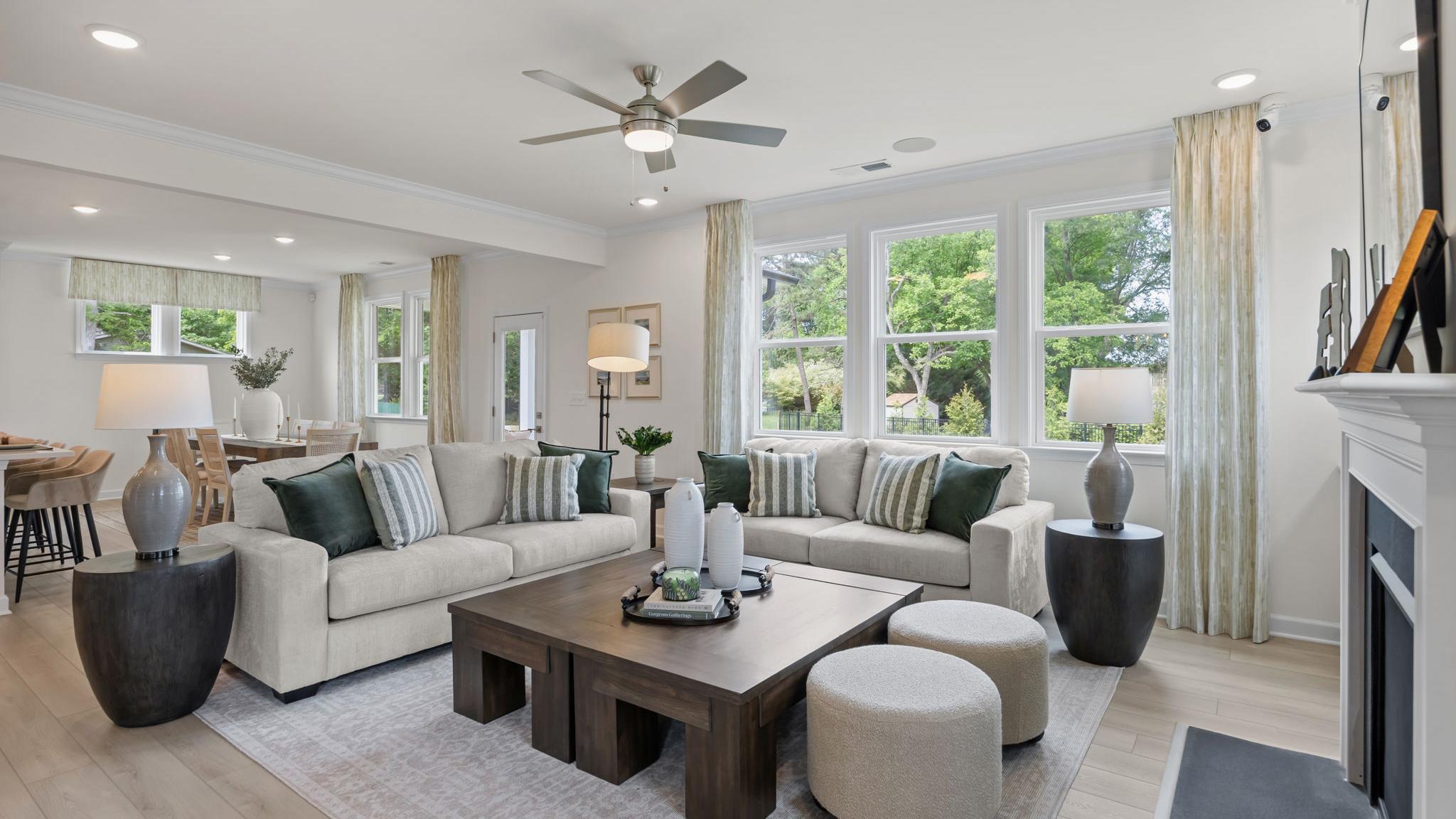 Modern open-concept kitchen in Windgate, Mooresville NC with white shaker cabinets, gray island, bar stools, stainless steel appliances, and hardwood floors