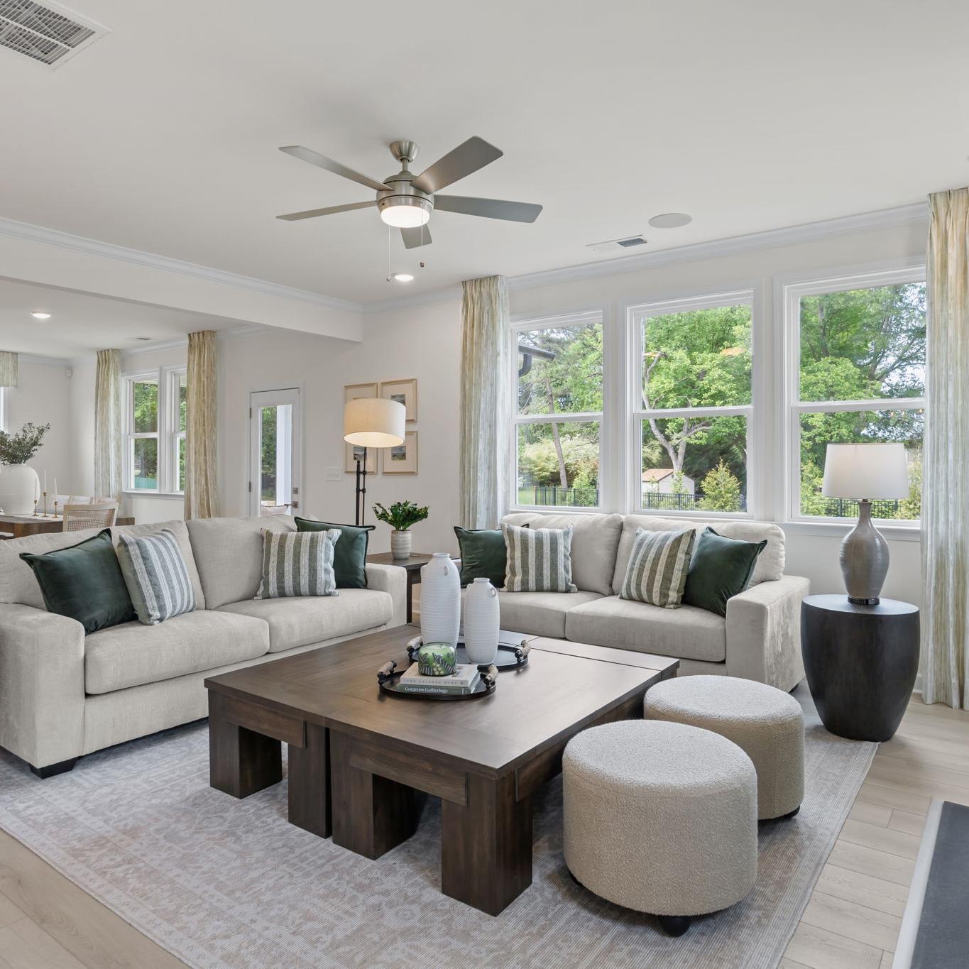 Modern open-concept kitchen in Windgate, Mooresville NC with white shaker cabinets, gray island, bar stools, stainless steel appliances, and hardwood floors