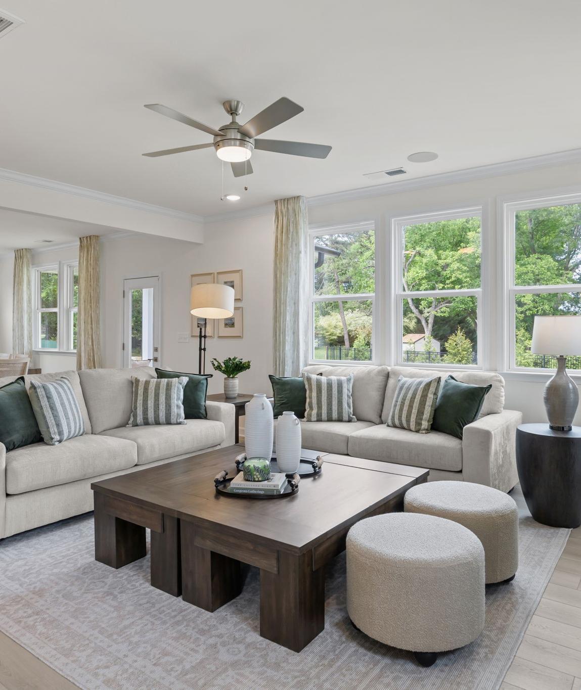Modern open-concept kitchen in Windgate, Mooresville NC with white shaker cabinets, gray island, bar stools, stainless steel appliances, and hardwood floors