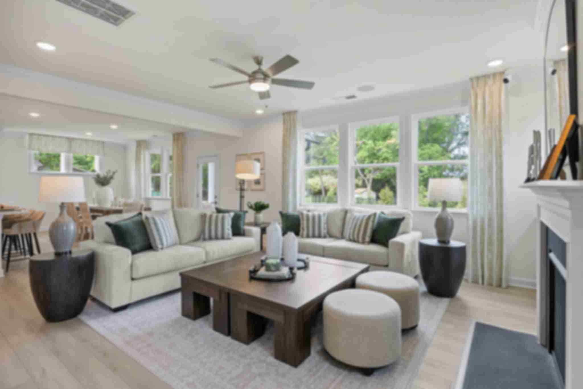 Modern open-concept kitchen in Windgate, Mooresville NC with white shaker cabinets, gray island, bar stools, stainless steel appliances, and hardwood floors
