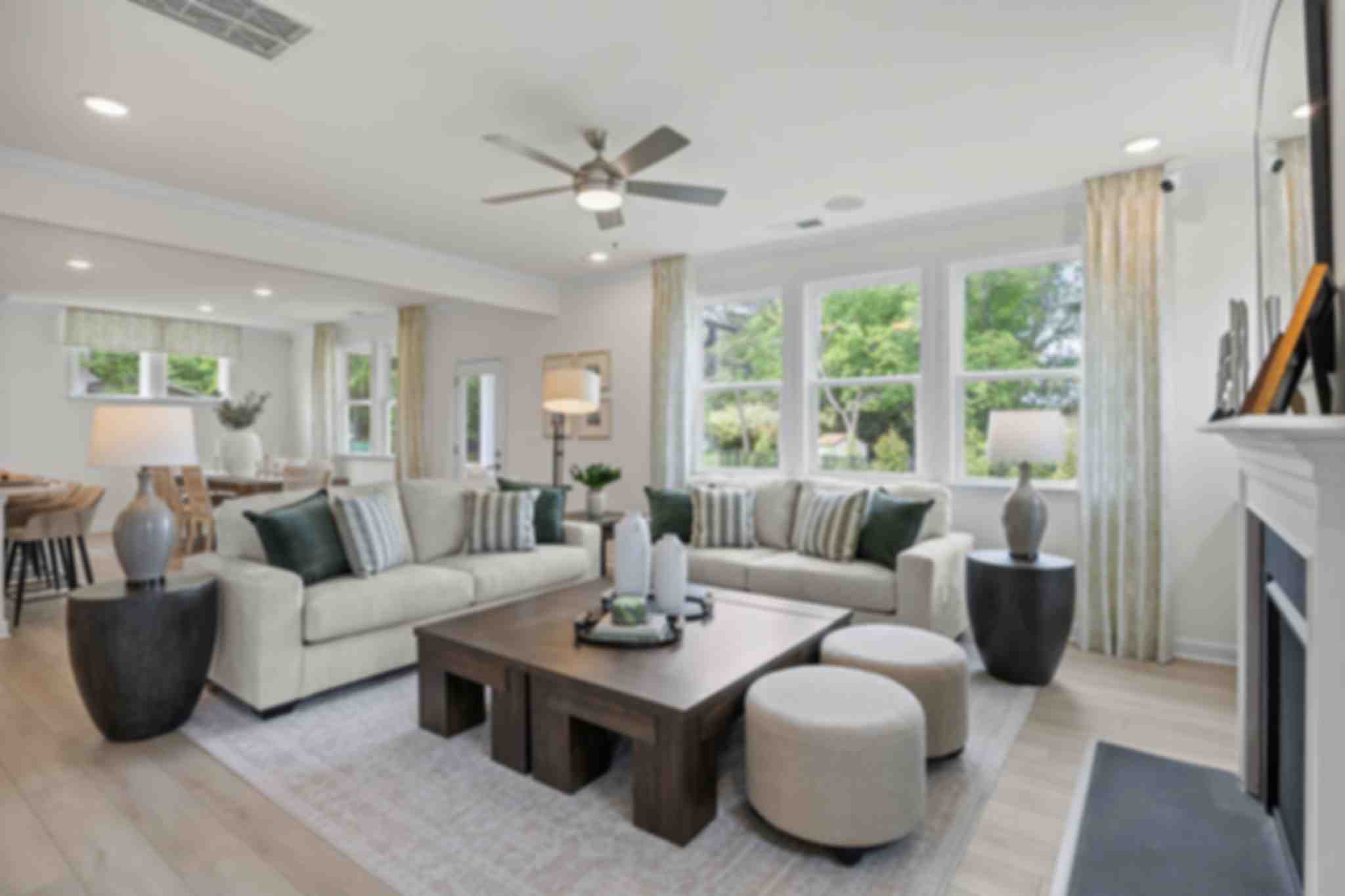 Modern open-concept kitchen in Windgate, Mooresville NC with white shaker cabinets, gray island, bar stools, stainless steel appliances, and hardwood floors