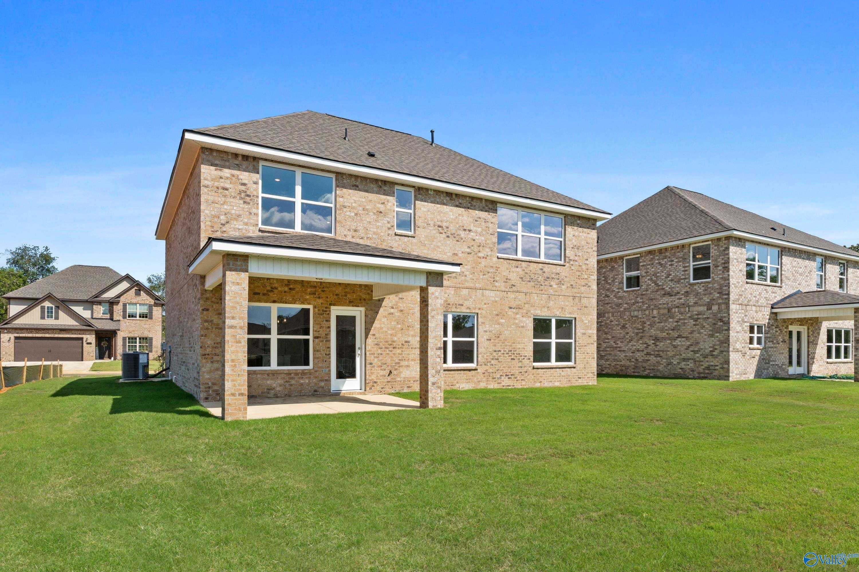 Two-story brick Shelby A home with covered side patio, two-car garage, and lush green yard in Creek Grove, New Market, Alabama