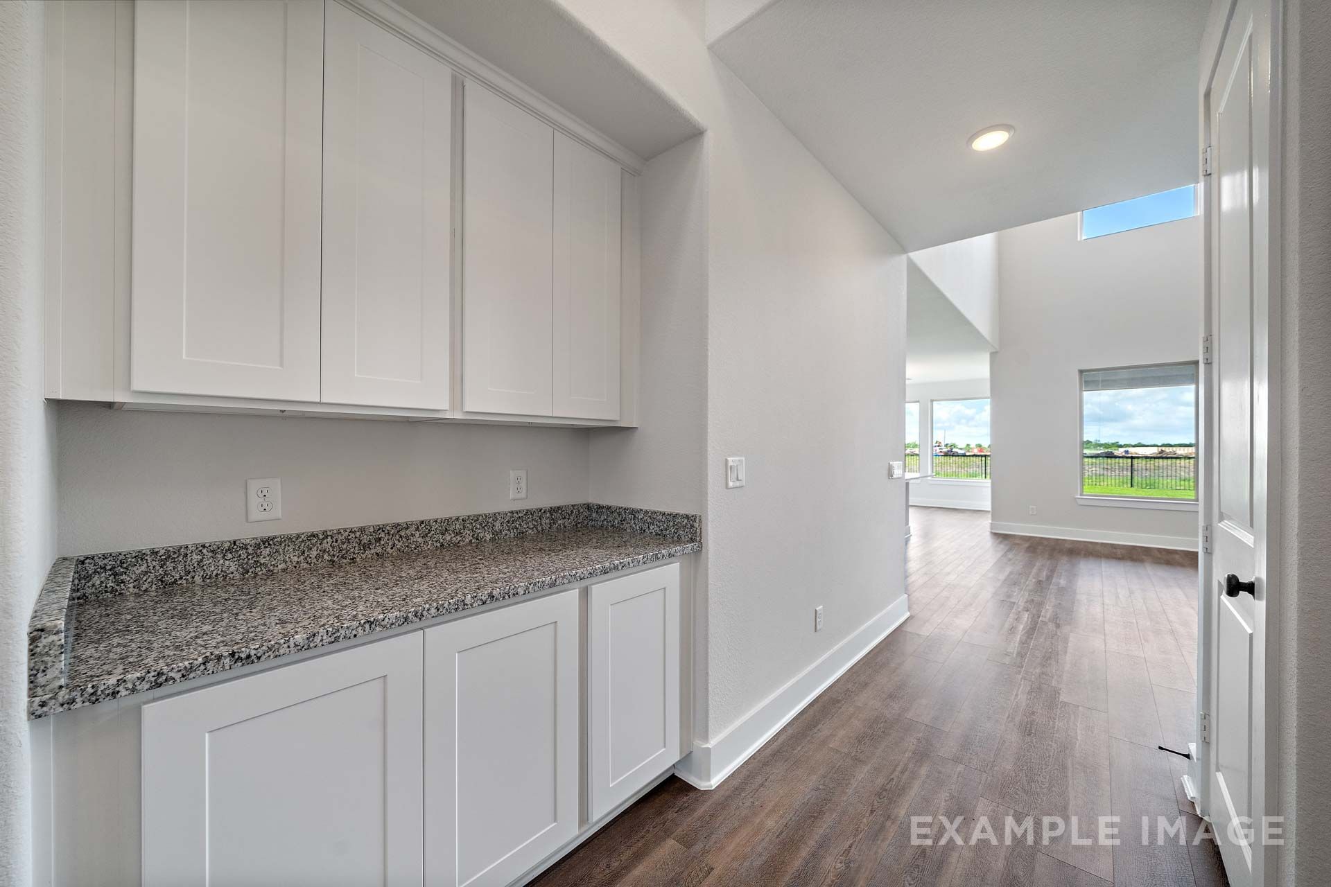 White shaker cabinetry with granite countertops in The Victoria by Davidson Homes, open to living area with wood-look flooring