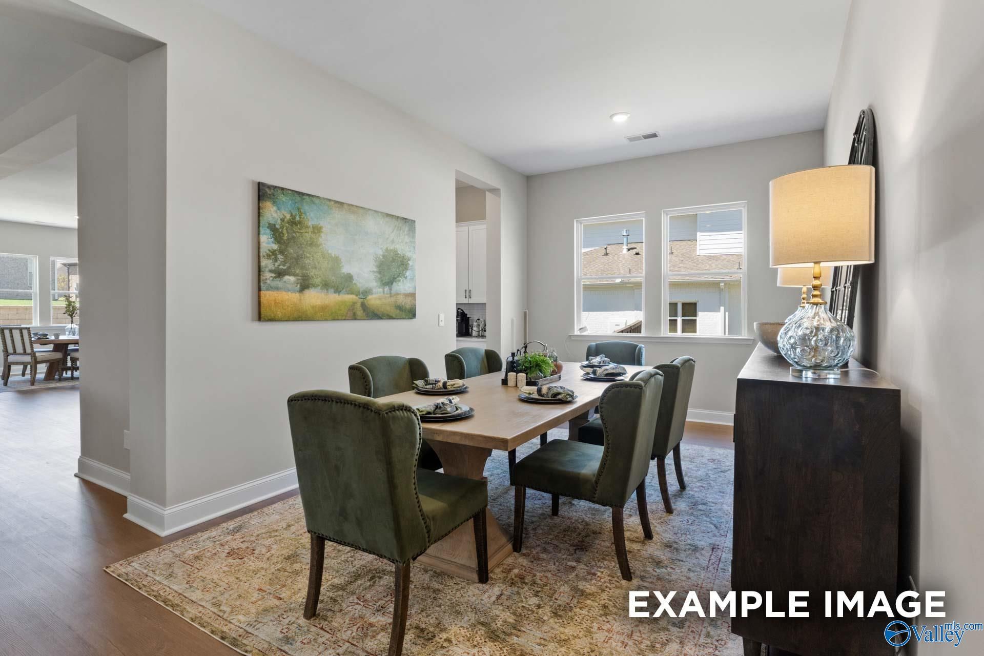 Elegant formal dining room featuring wooden table, green velvet chairs, and landscape wall art in Evermore Homes The Haven E, Owens Cross Roads, AL