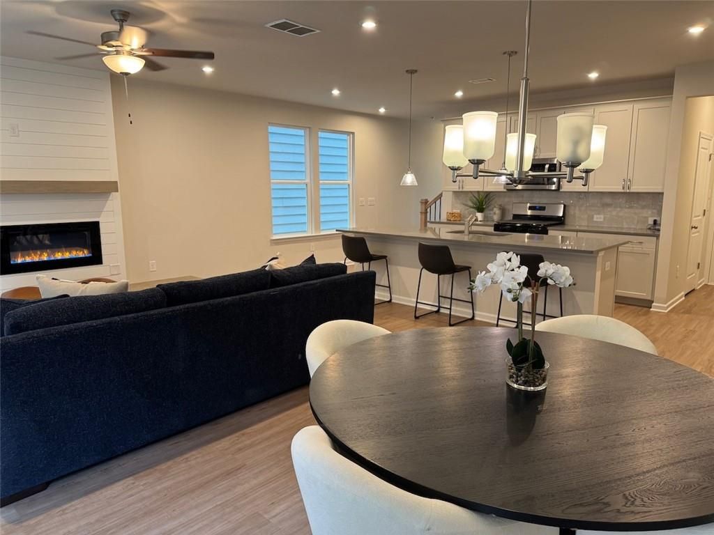 Open-concept living room with gas fireplace, navy sectional sofa, round dining table, and white kitchen island in Davidson Homes The Cary A, Kennesaw, GA