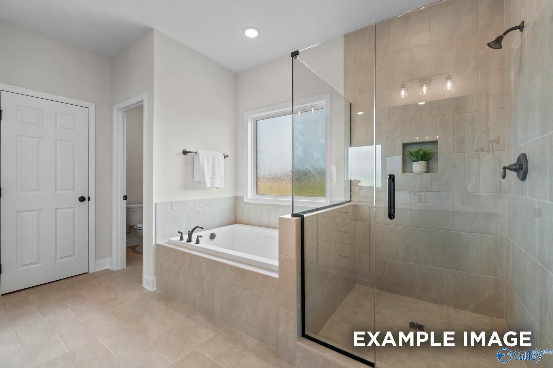 Modern master bathroom with frameless glass shower, soaking tub, and frosted window in Davidson Homes The Kirkland, Decatur, AL