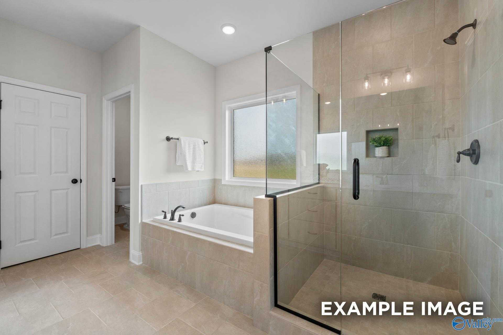 Modern master bathroom with freestanding tub, glass shower, and frosted window in Davidson Homes The Kirkland, Decatur, Alabama