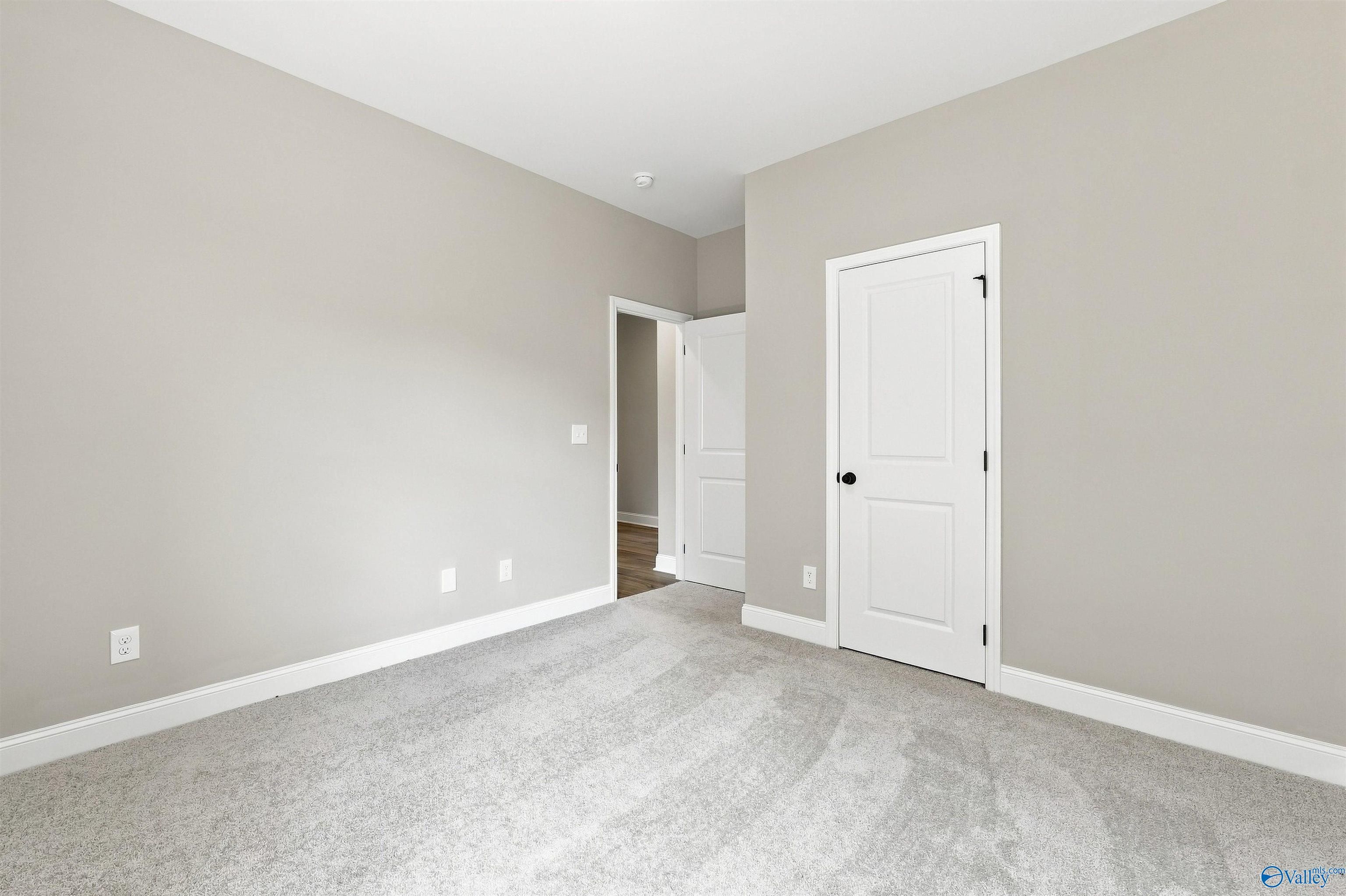 Bright carpeted bedroom with neutral walls and white doors in Davidson Homes Franklin C plan, Wood Trail, Toney, Alabama