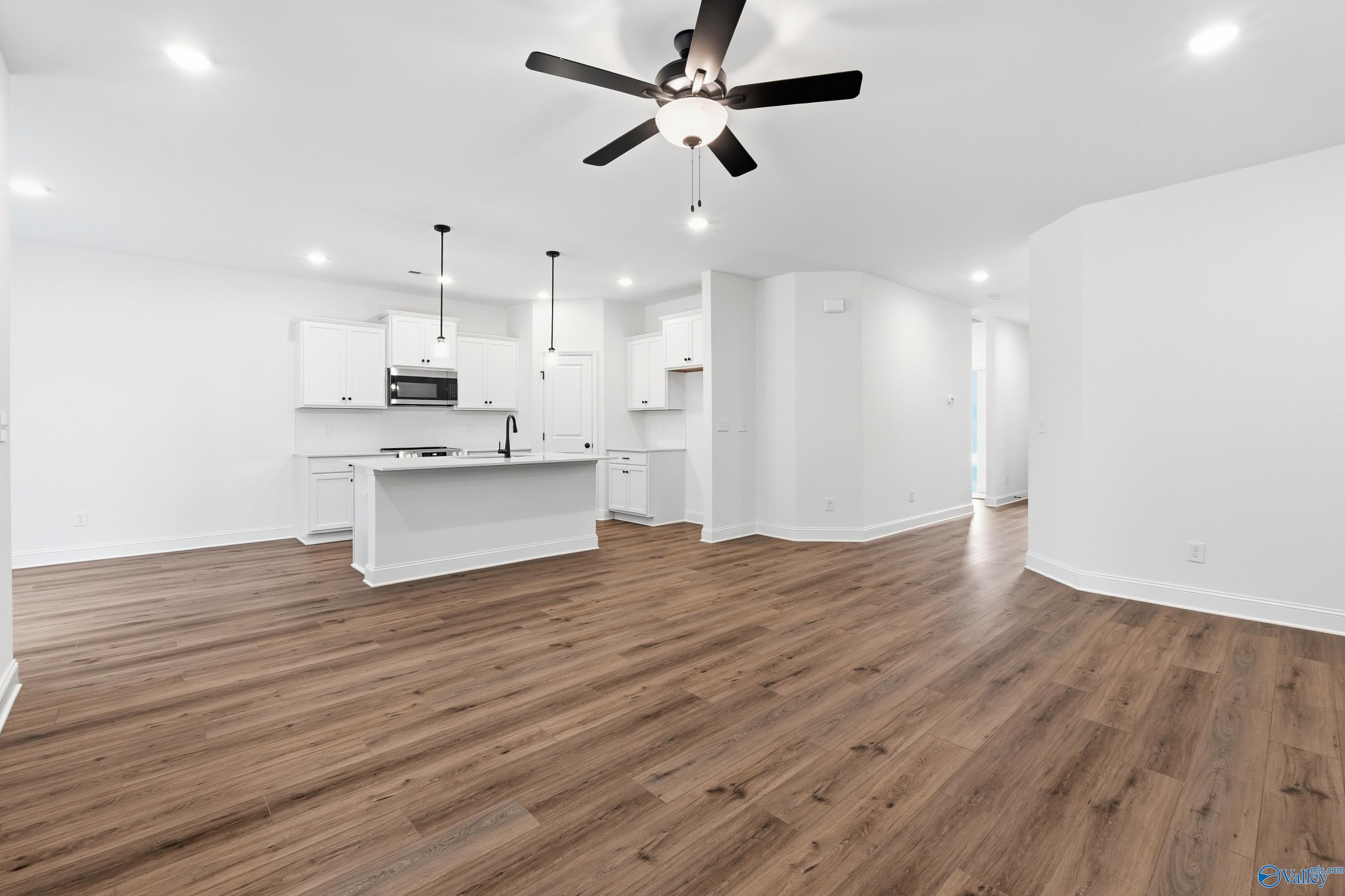 Open-concept kitchen and living area with wood-style flooring in The Asheville C floor plan, The Highlands, Arab, Alabama.
