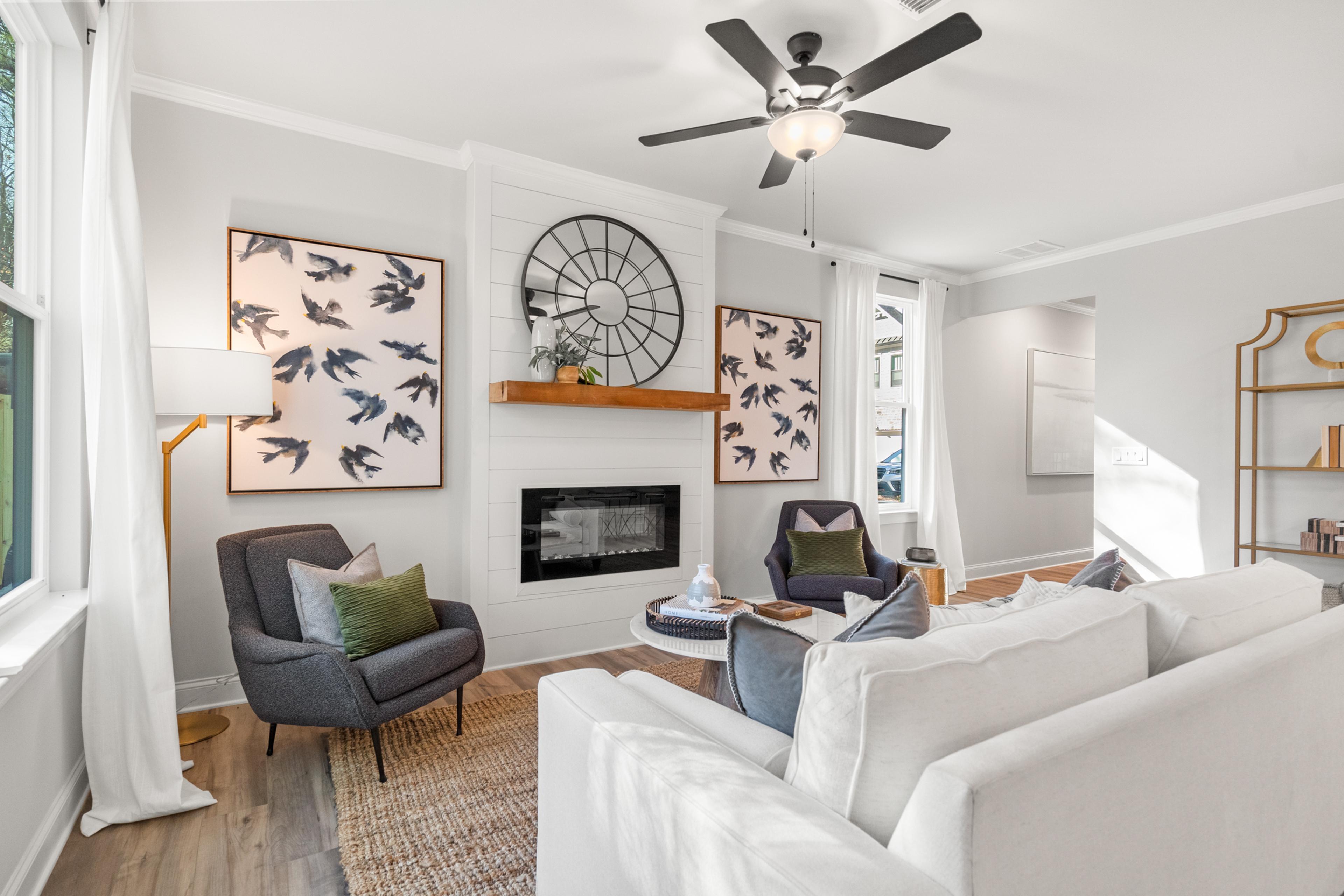 Modern living room with gas fireplace, white sofas, bird art, and ceiling fan at The Village at Towne Lake, Woodstock GA by Davidson Homes
