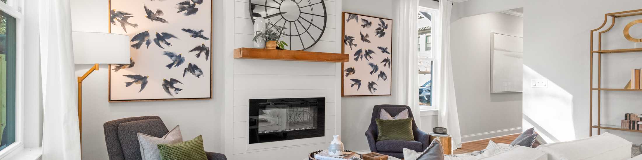 Modern living room with gas fireplace, white sofas, bird art, and ceiling fan at The Village at Towne Lake, Woodstock GA by Davidson Homes