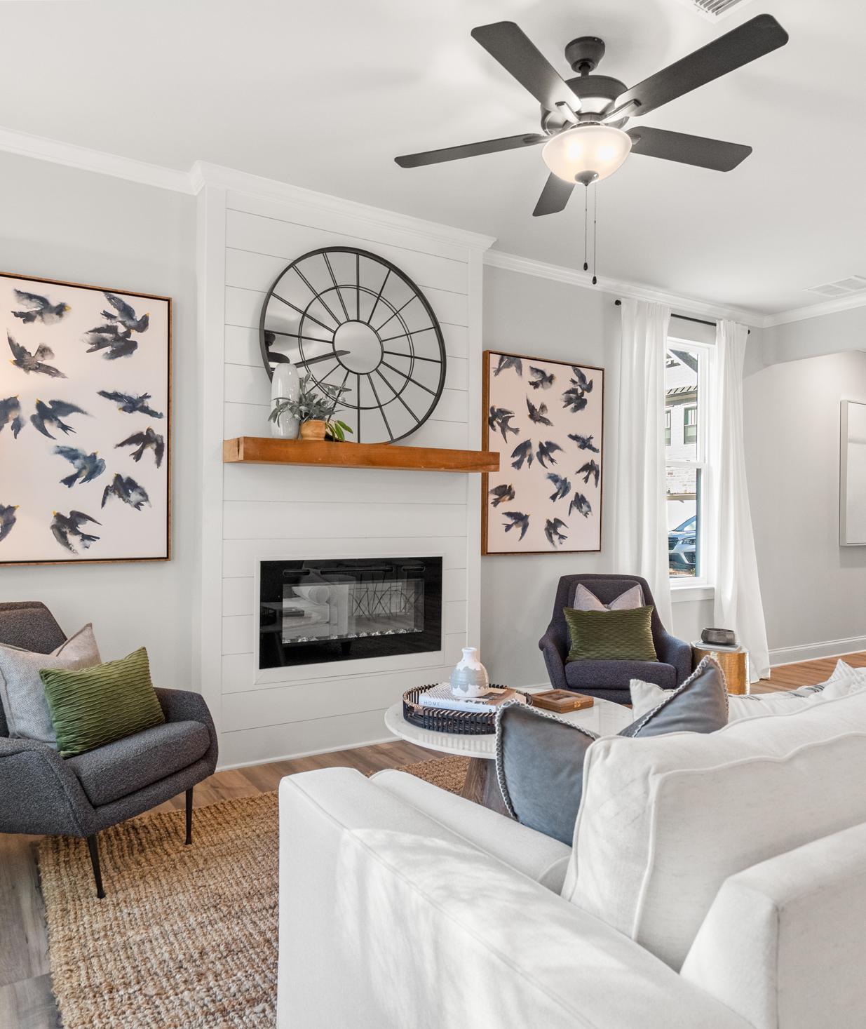 Modern living room with gas fireplace, white sofas, bird art, and ceiling fan at The Village at Towne Lake, Woodstock GA by Davidson Homes
