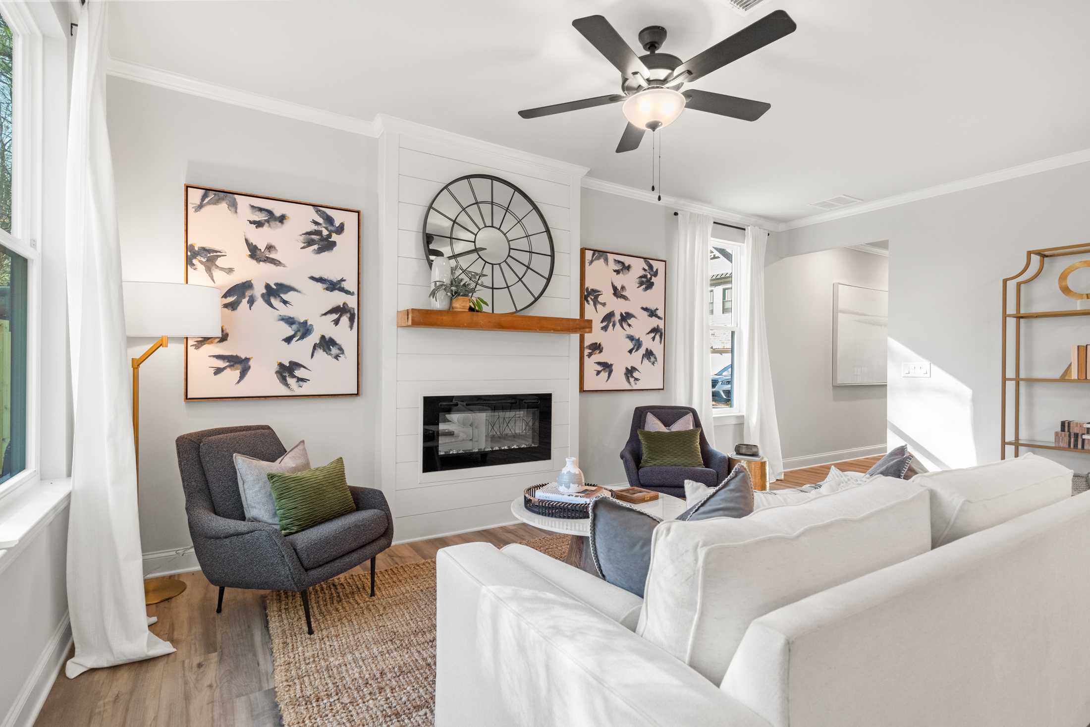 Modern living room with gas fireplace, white sofas, bird art, and ceiling fan at The Village at Towne Lake, Woodstock GA by Davidson Homes