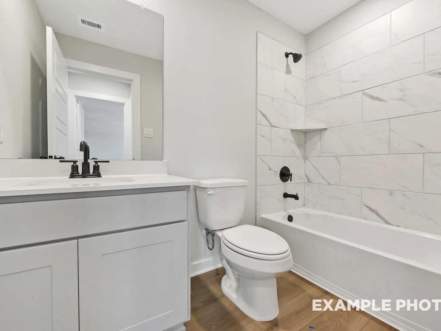 Modern bathroom with white vanity, marble-style tile shower surround, and matte black fixtures in Sundance Cove home.