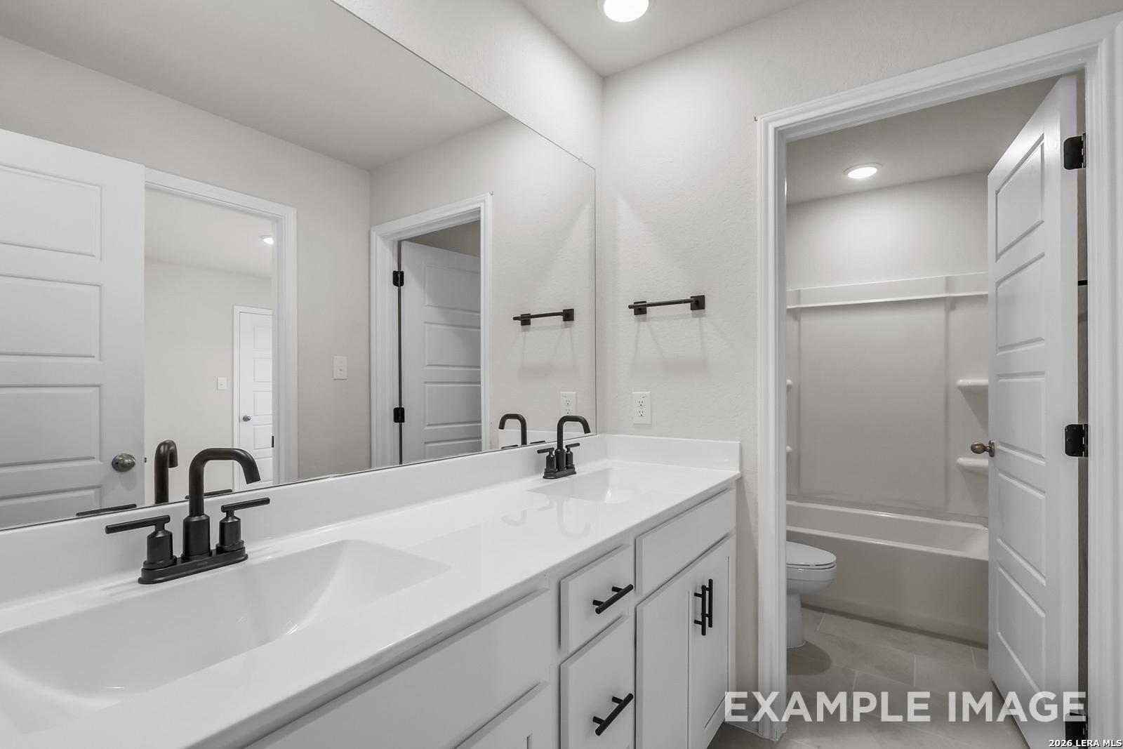 Modern bathroom with dual vanity, matte black fixtures, and tub-shower combo in Davidson Homes' Sequoia C, San Antonio.