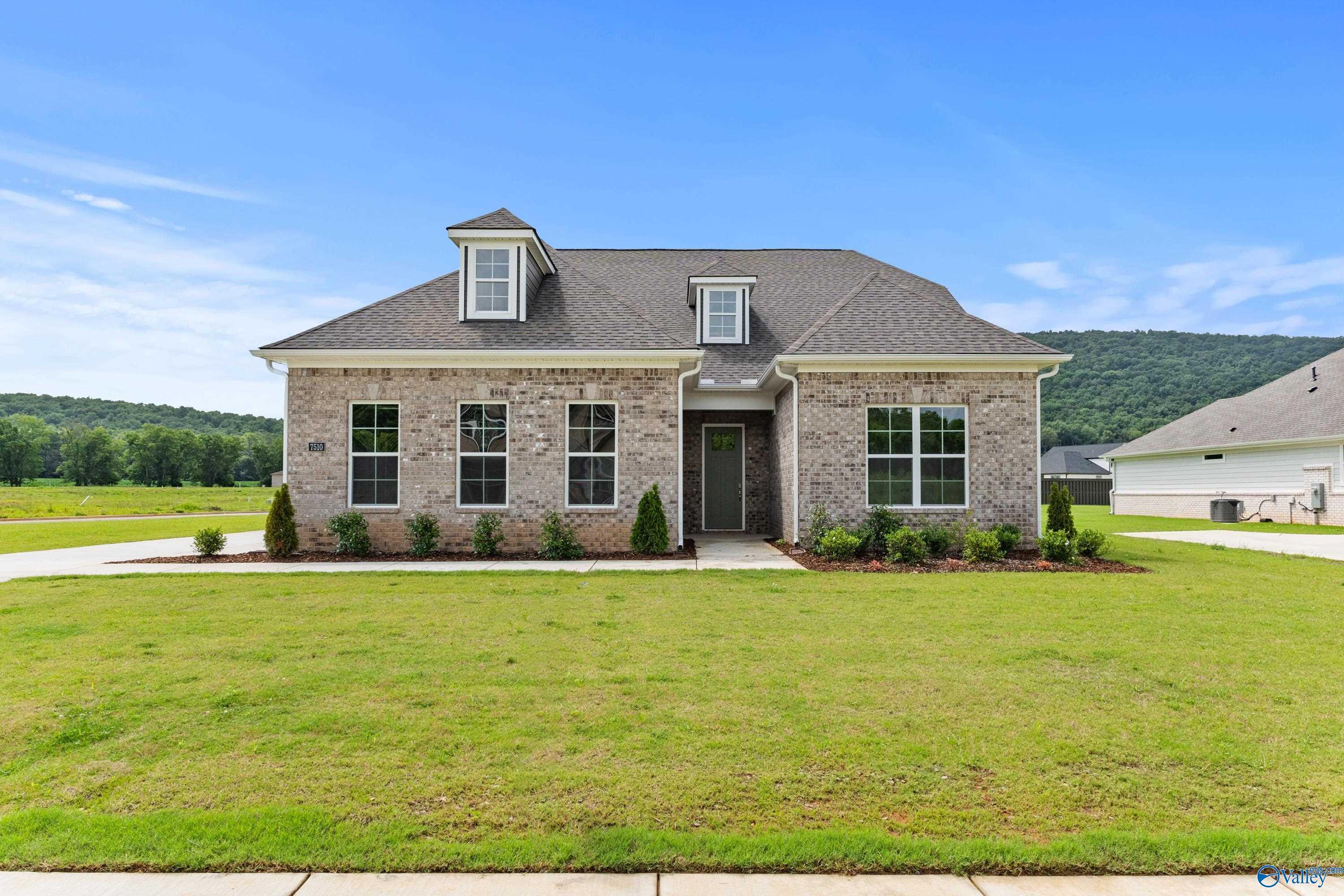 Brick 1.5-story Oxford B home with gabled roof, dormers, and landscaped front yard in The Meadows at Hampton Cove, Owens Cross Roads, Alabama