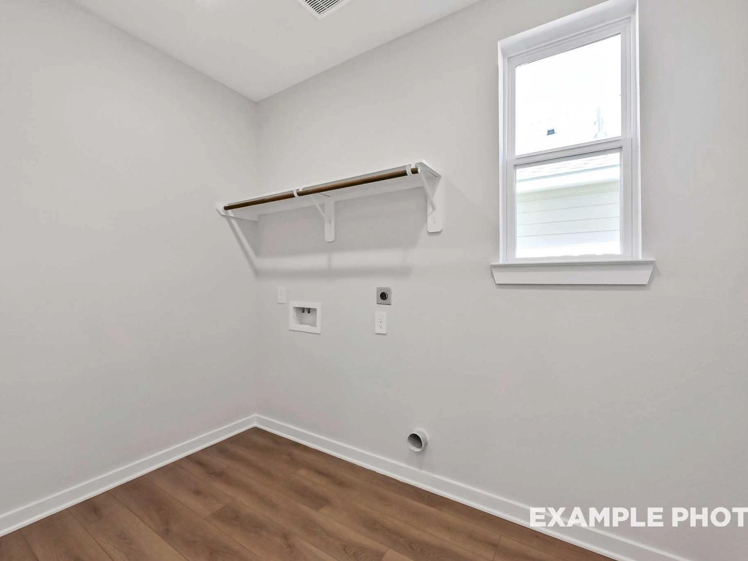 Laundry room with wood-look flooring and built-in shelving in The Sequoia C floor plan at Sundance Cove in Crosby, Texas.