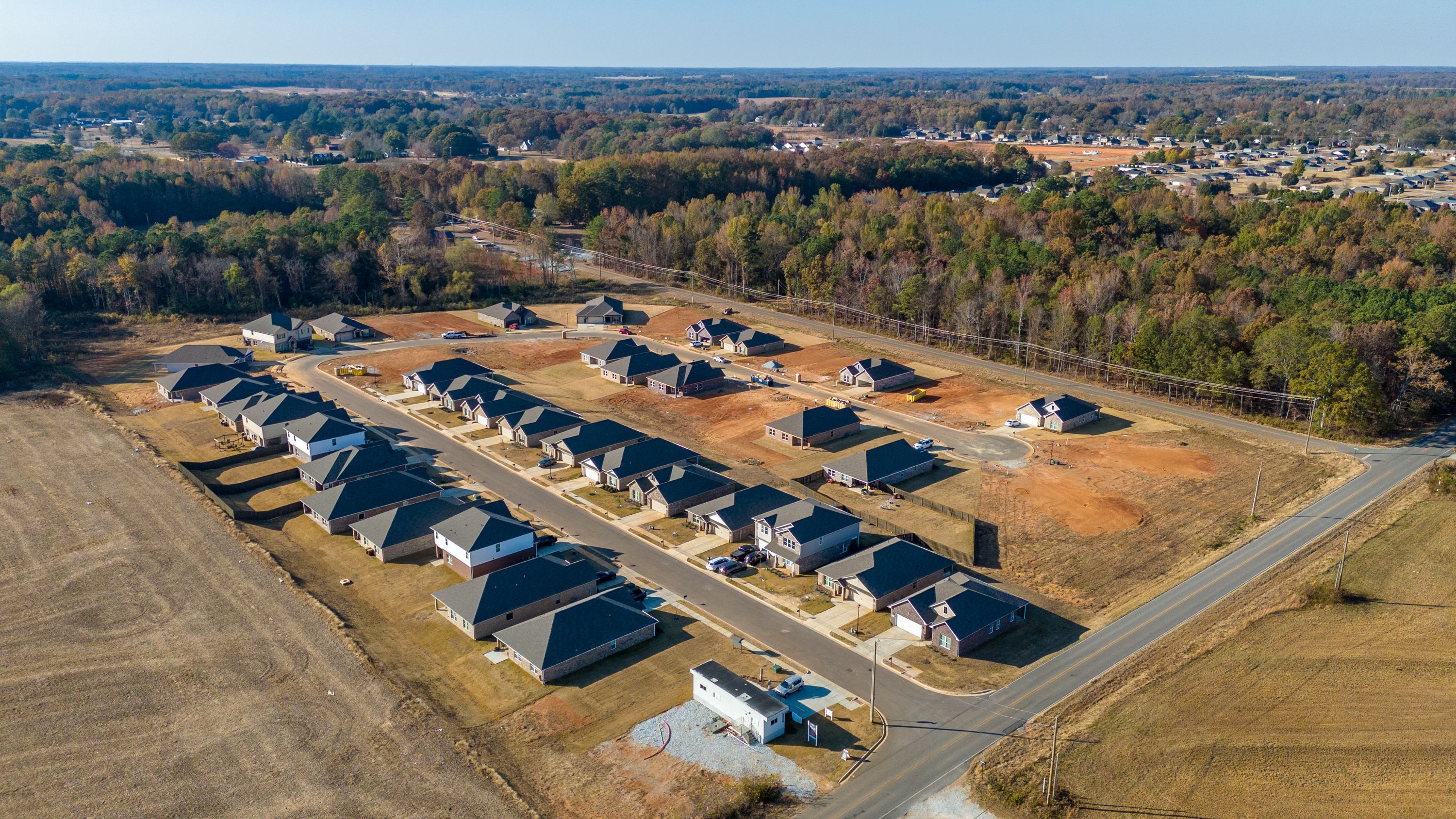 Aerial view of new homes in Mallard Landing, Athens Alabama with dark roofs, open lots and wooded fields
