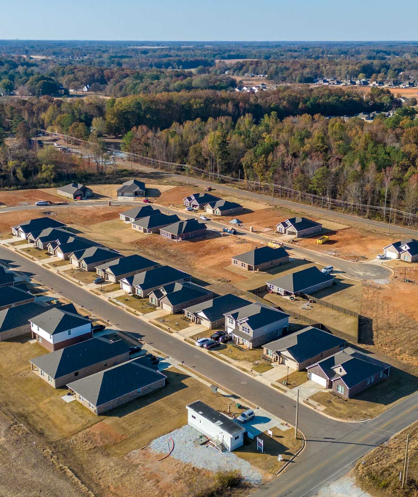 Aerial view of new homes in Mallard Landing, Athens Alabama with dark roofs, open lots and wooded fields